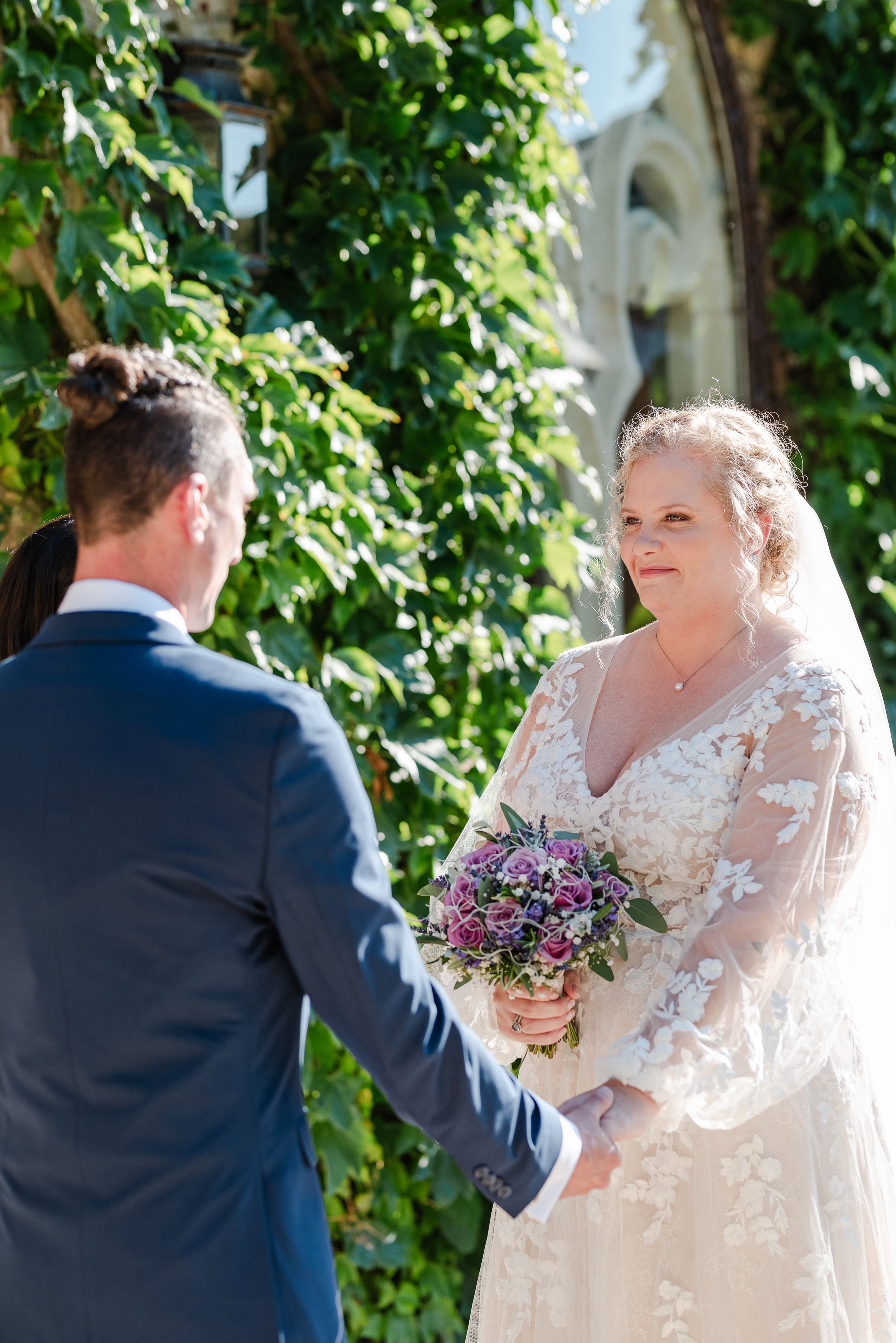 Bride smiling at groom during an intimate wedding in France surrounded by ivy-covered walls