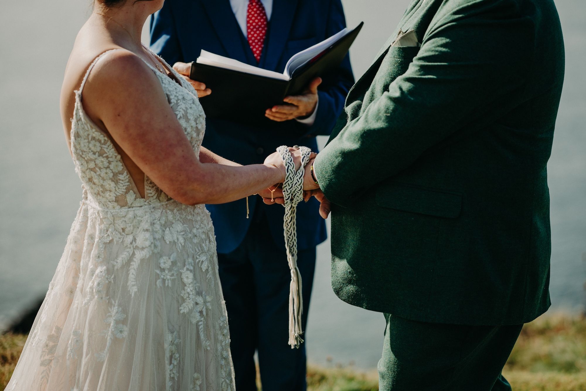 Bride and groom's hands and arms during the Celtic handfasting ceremony of their elopement in Ireland