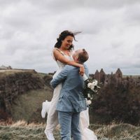 Groom lifting up his bride in front of Dunluce Castle in Northern Ireland
