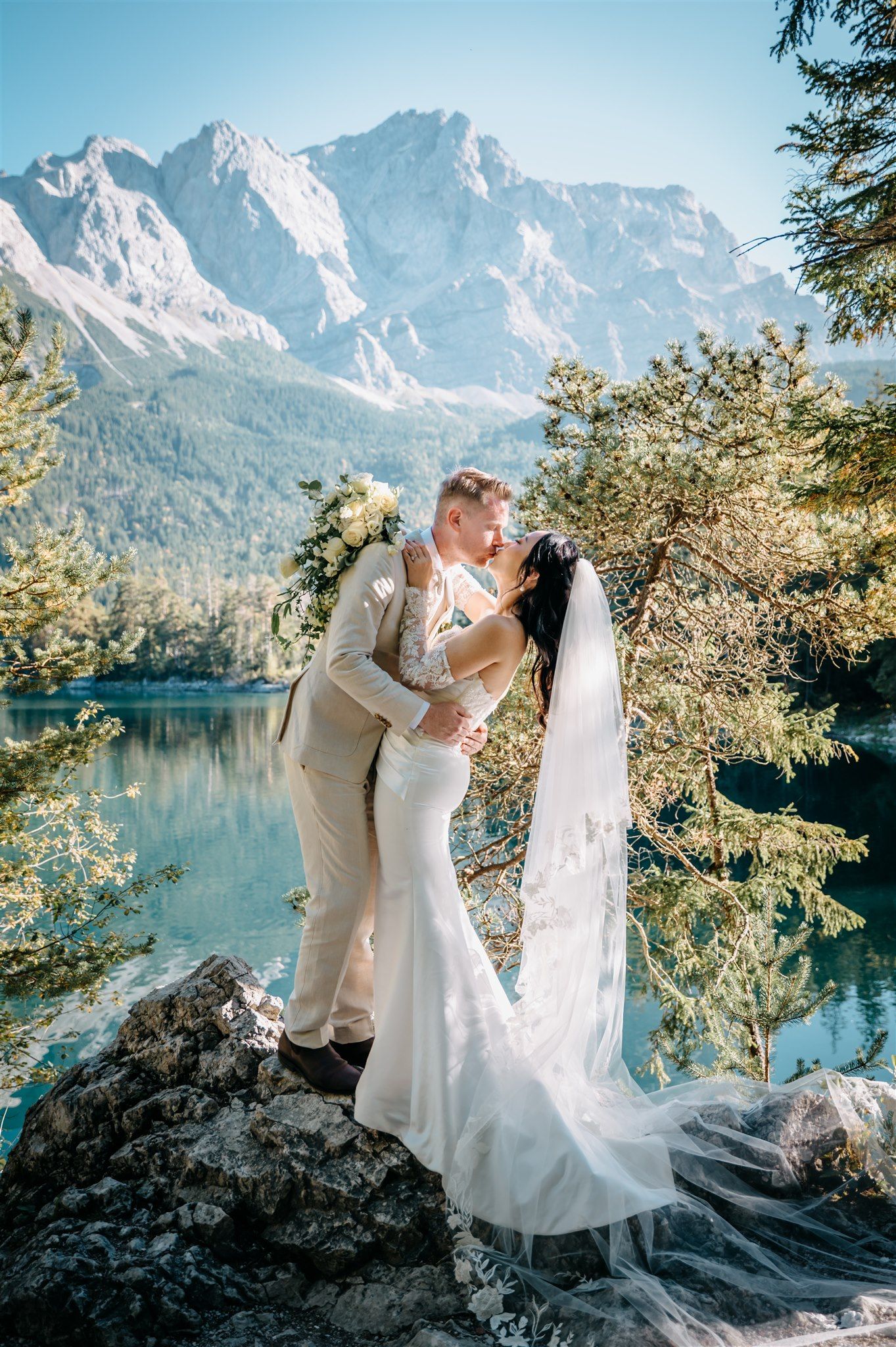 A bride and groom kissing with the lake and mountains behind them during their intimate wedding in Germany