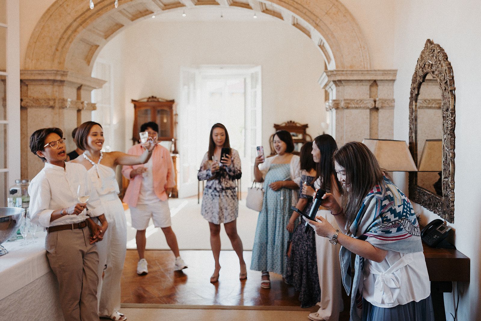 Newlyweds laughing with guests during the party of their micro wedding in Portugal inside a hotel's event room along Cascais