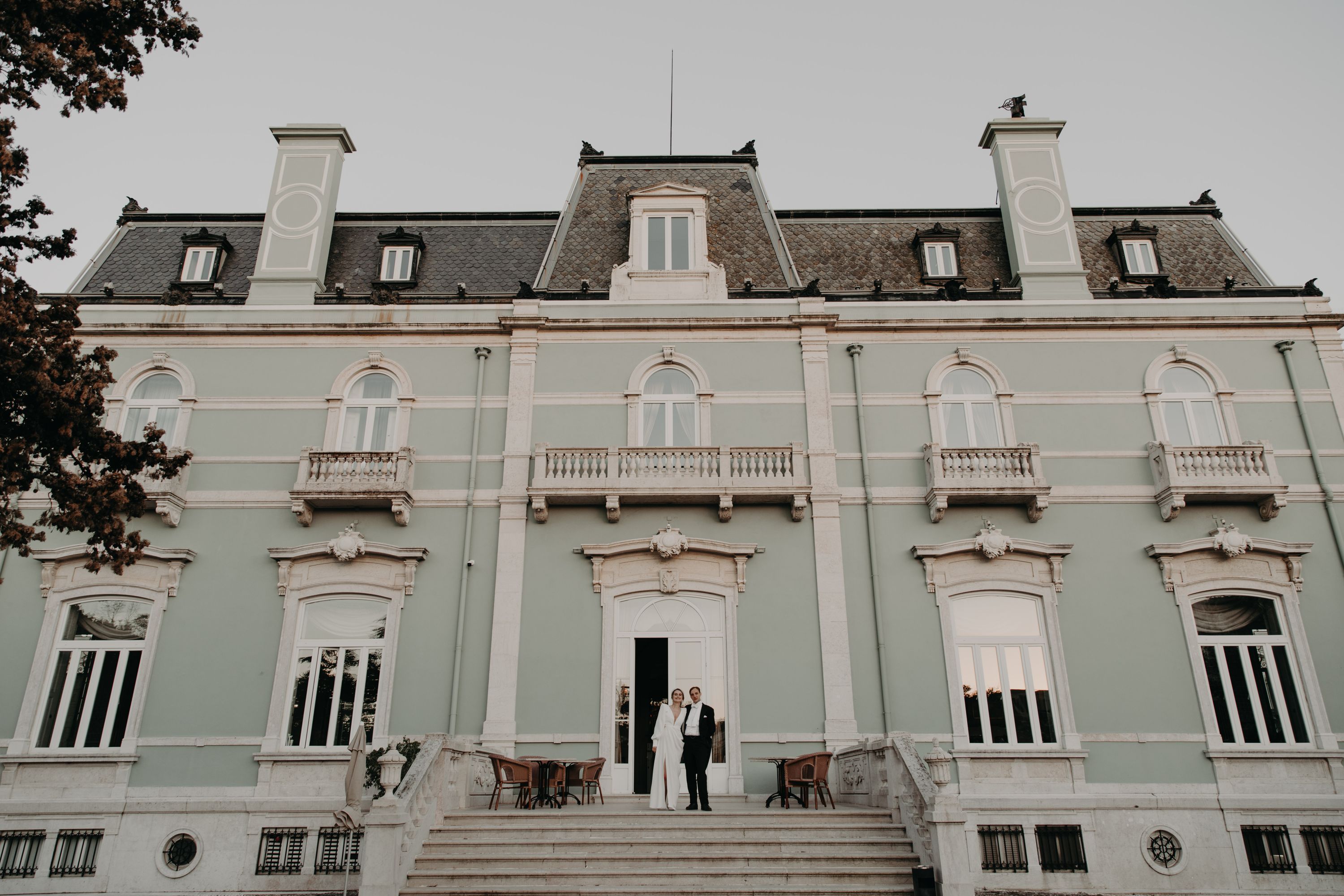 Bride and groom standing in front of a blue palace in Lisbon that was the venue for their winter wedding in Portugal
