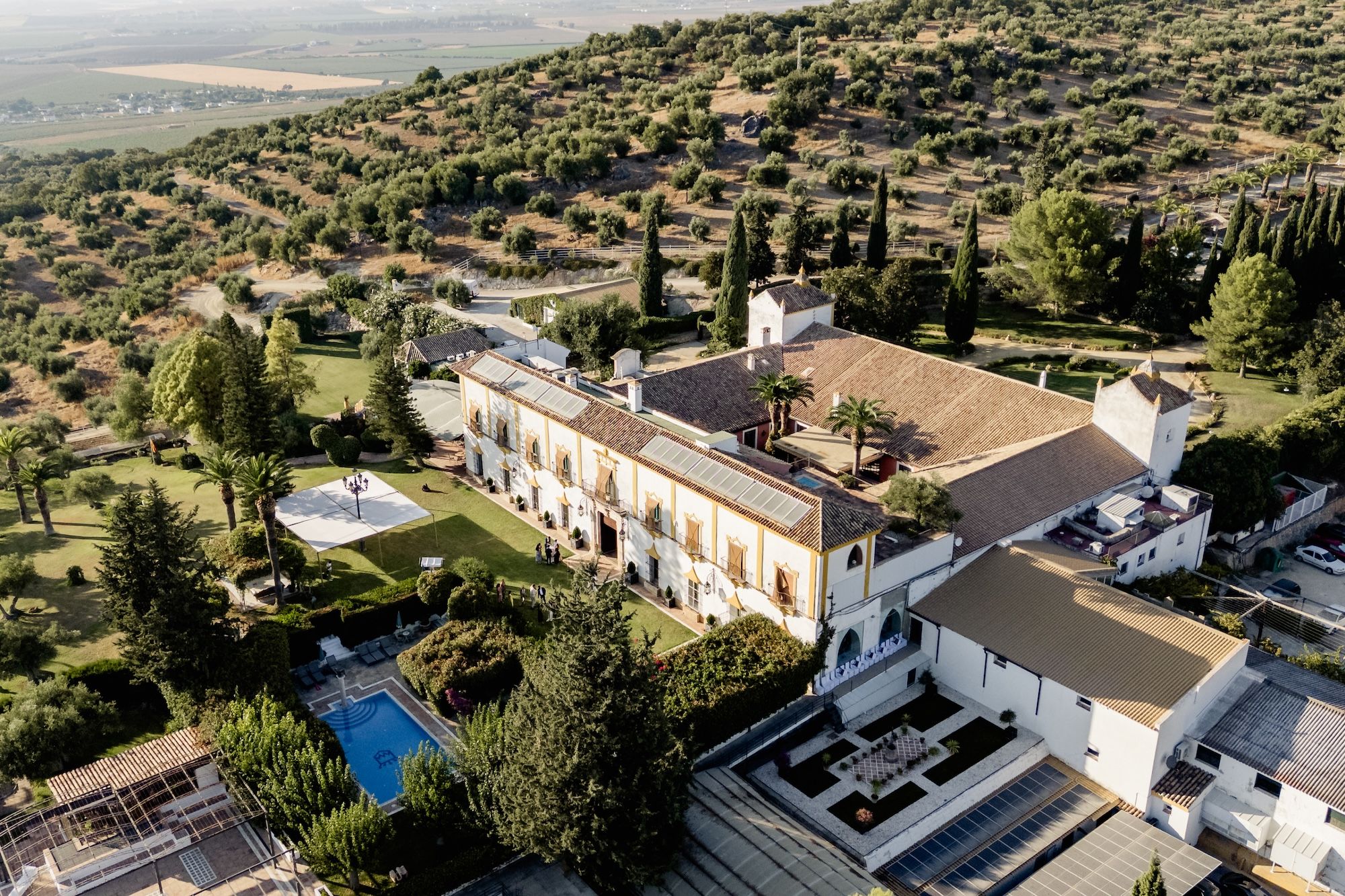 A large country house with a pool in front surrounded by the lush green landscapes of Cadiz in Spain