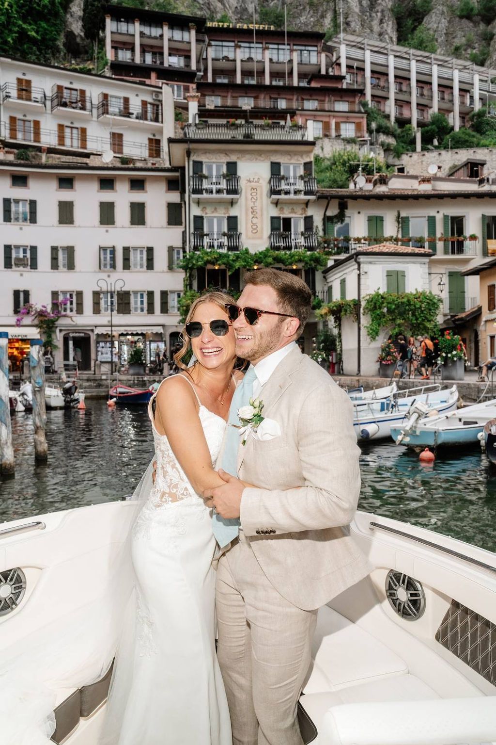 Bride hugs her groom while they ride a boat along Lake Garda after the ceremony of their elopement in Italy in Veneto
