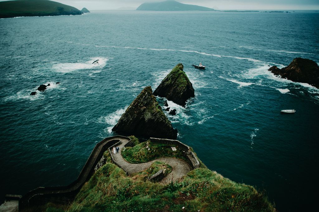 Wide shot of the Dunquin Pier with the Atlantic Ocean in the background and the couple barely seen walking on the zigzag path