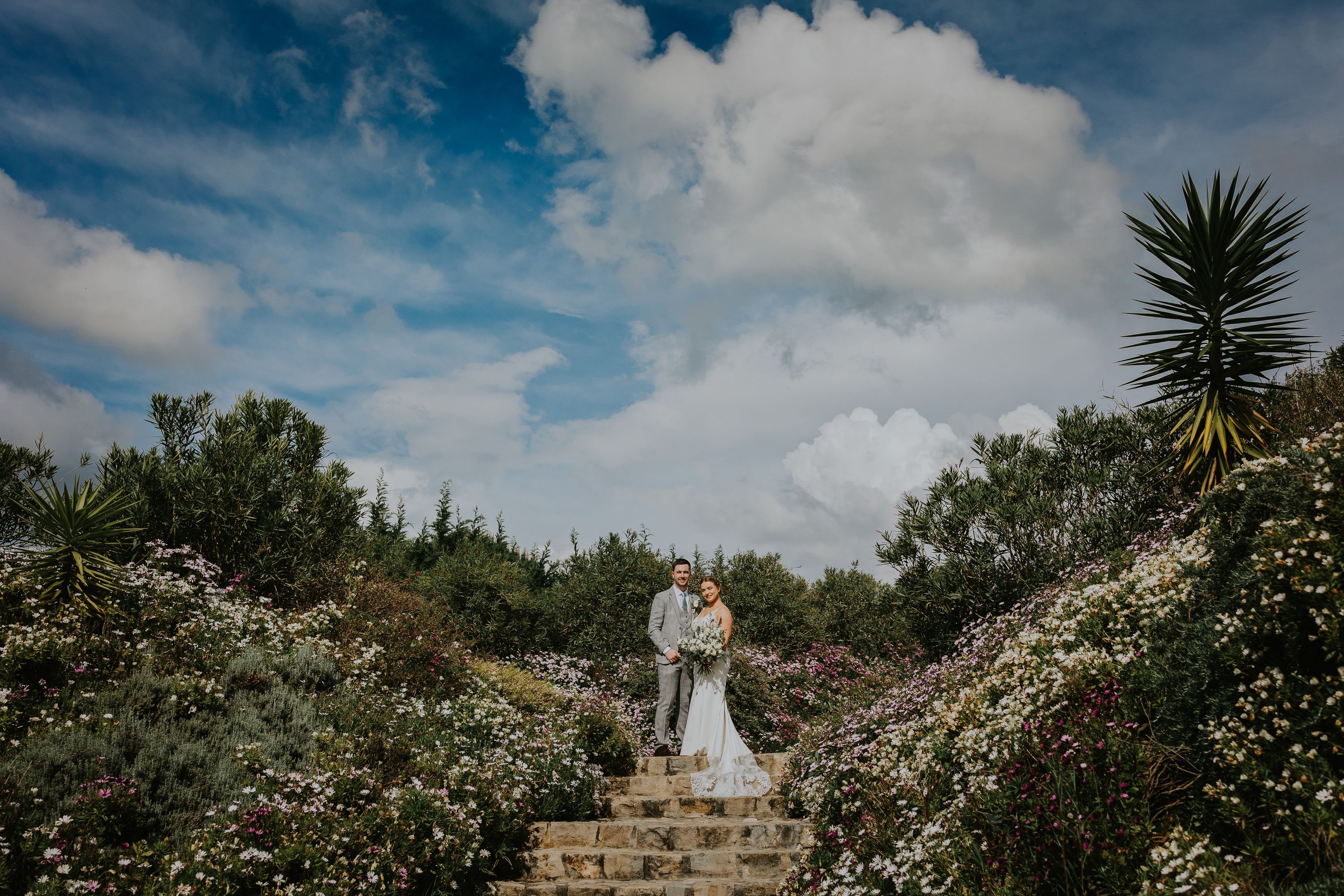 Bride and groom surrounded by greenery and vibrant spring flowers in Mafra when they got married in Portugal