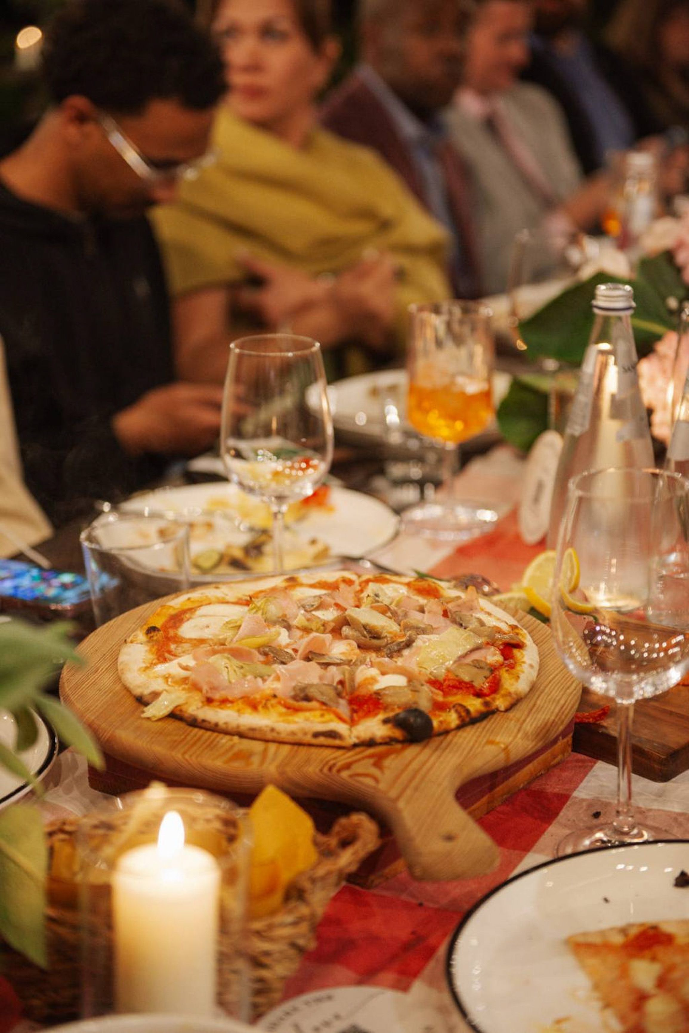 Guests enjoy wood-fired pizza and candlelit dining during an intimate wedding in Italy reception celebration