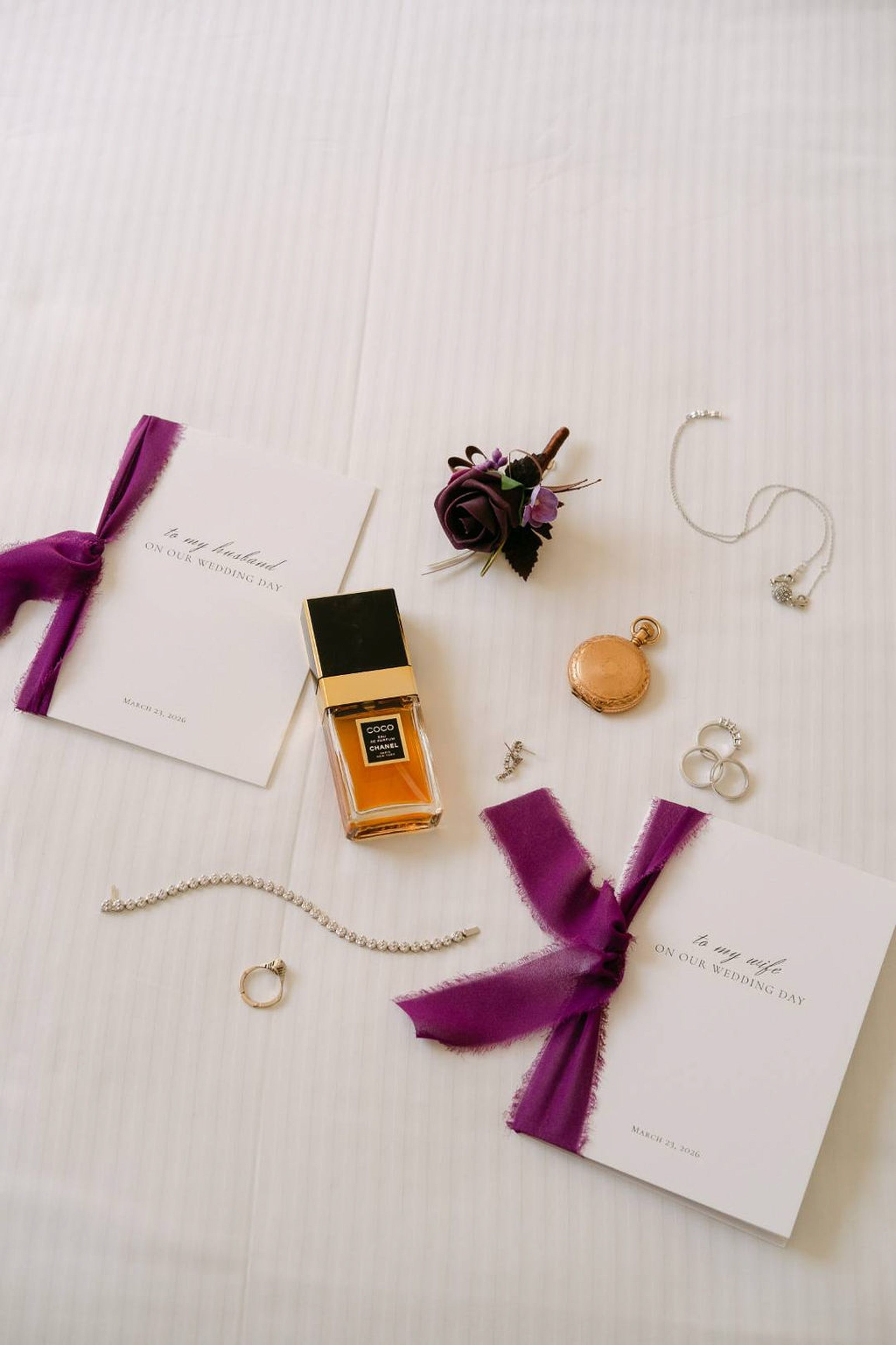 Wedding flat lay with vows, rings, perfume and purple details for a small wedding in Italy