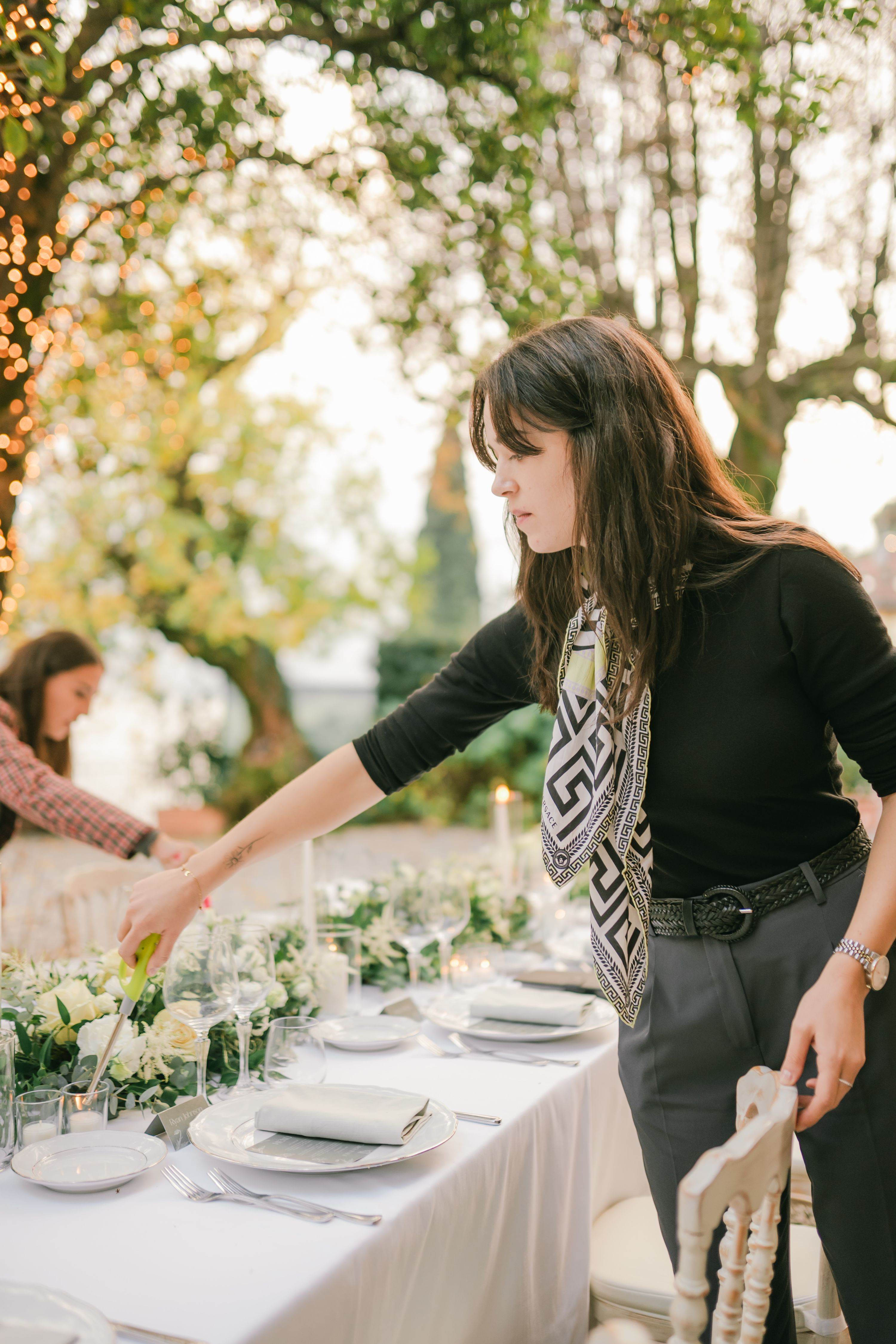 Our destination wedding planner in Italy lights a candle at a long table for the reception of a vow renewal in Italy