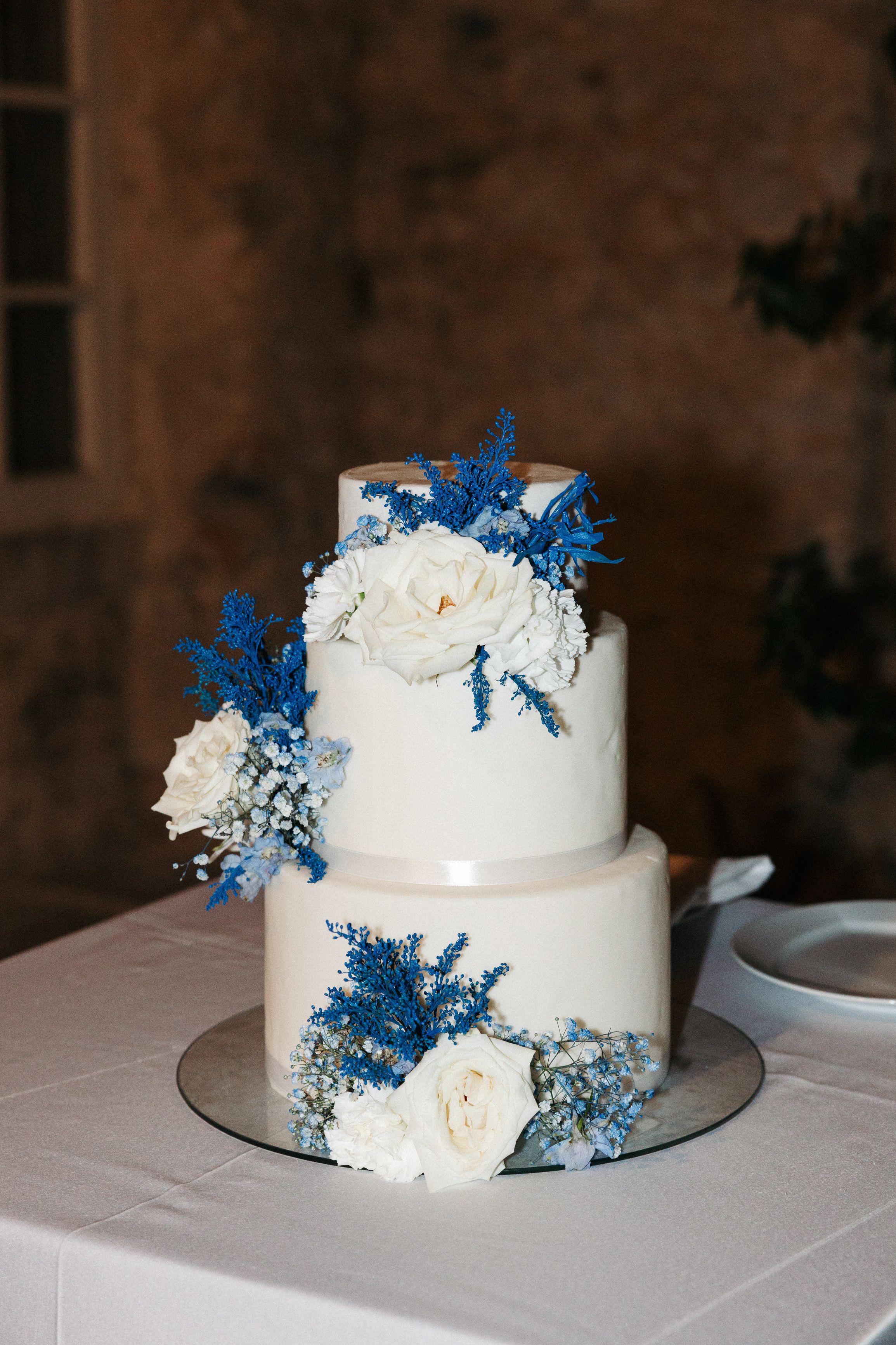 Modern white wedding cake decorated with blue and white floral accents at an intimate wedding in Portugal