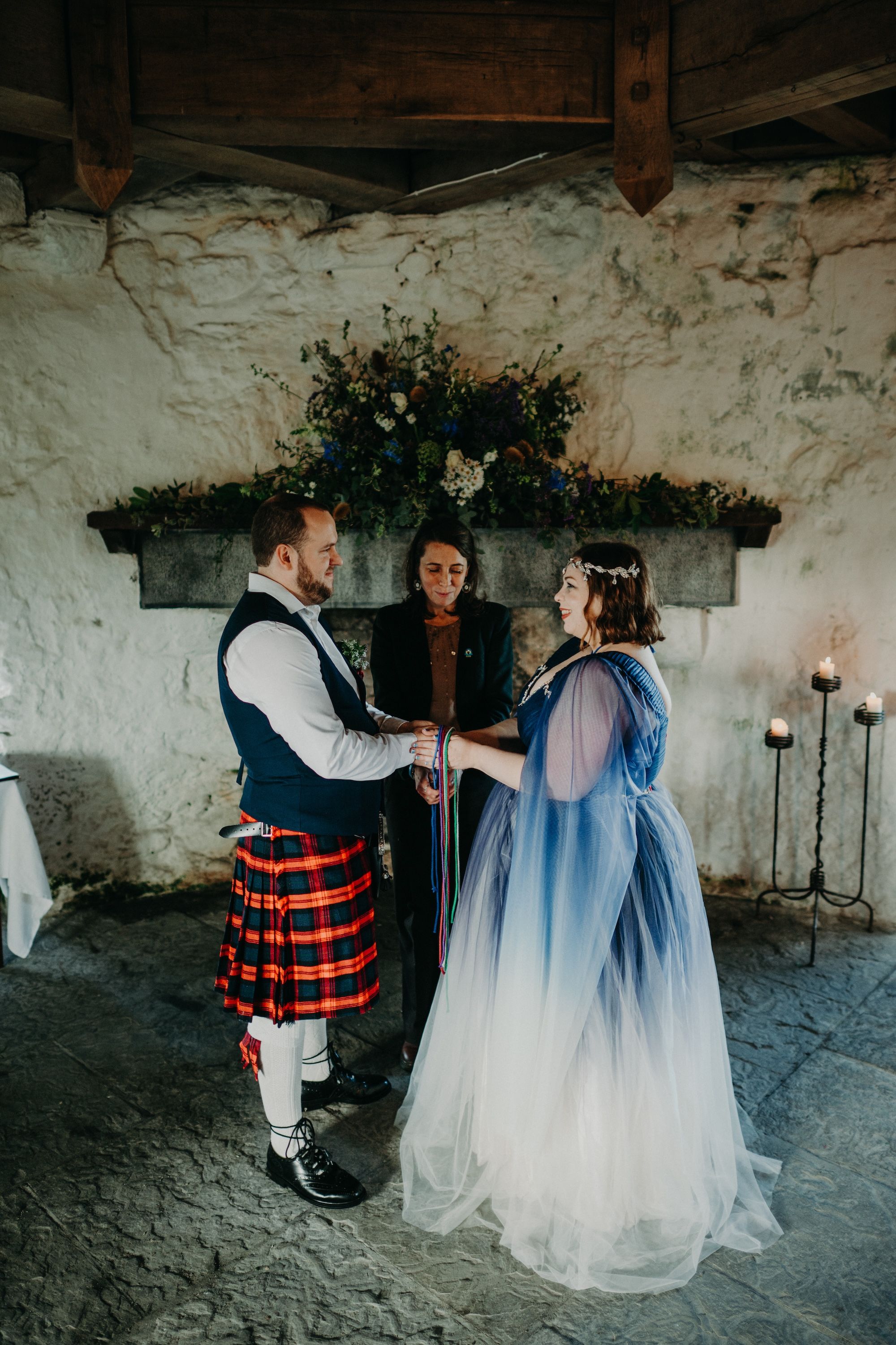Bride and groom hold hands in front of their celebrant during the ceremony of their elopement in Ireland
