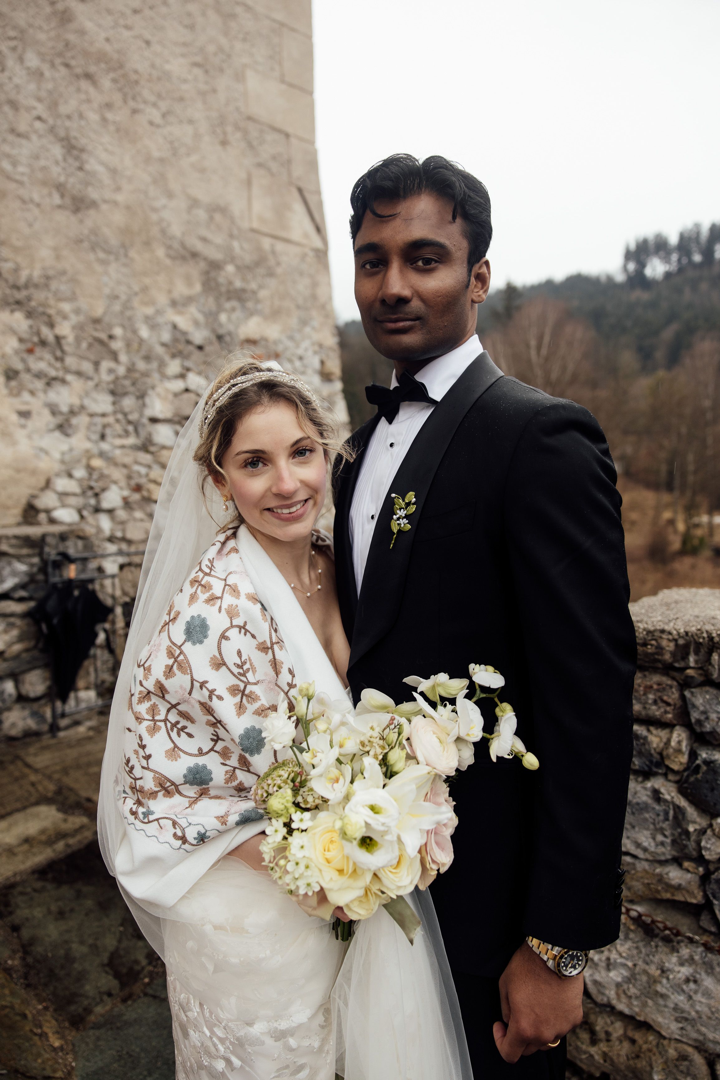Newlyweds pose with mountain views and a bouquet after a small wedding in Austria