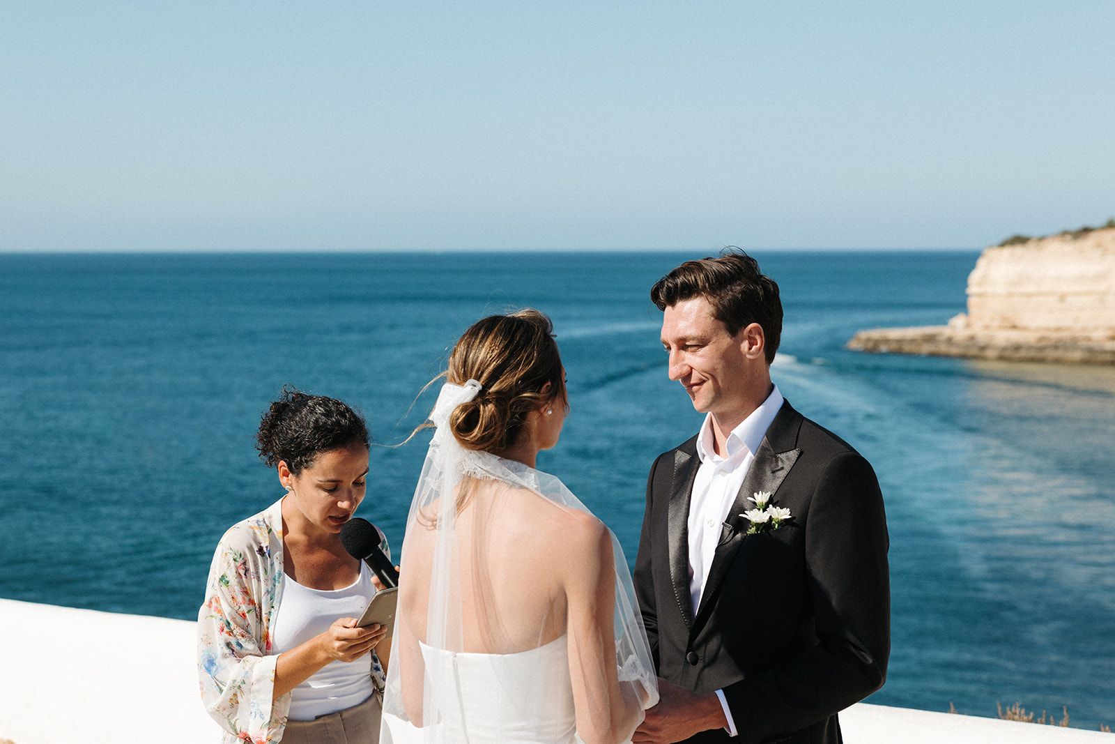Bride and groom having an outdoor ceremony atop the cliffs in Algarve for their destination wedding in Portugal.