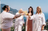 Bride gets ready for the ceremony of her micro wedding in Italy with her family having cocktails atop the hotel's terrace