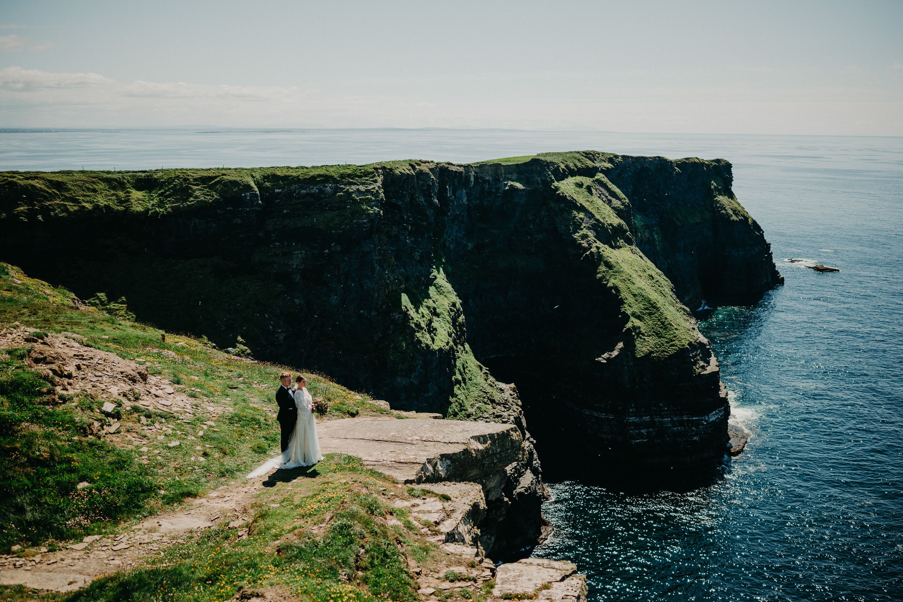 A bride and groom looking at each other while standing on top of a cliff after their intimate wedding in Ireland