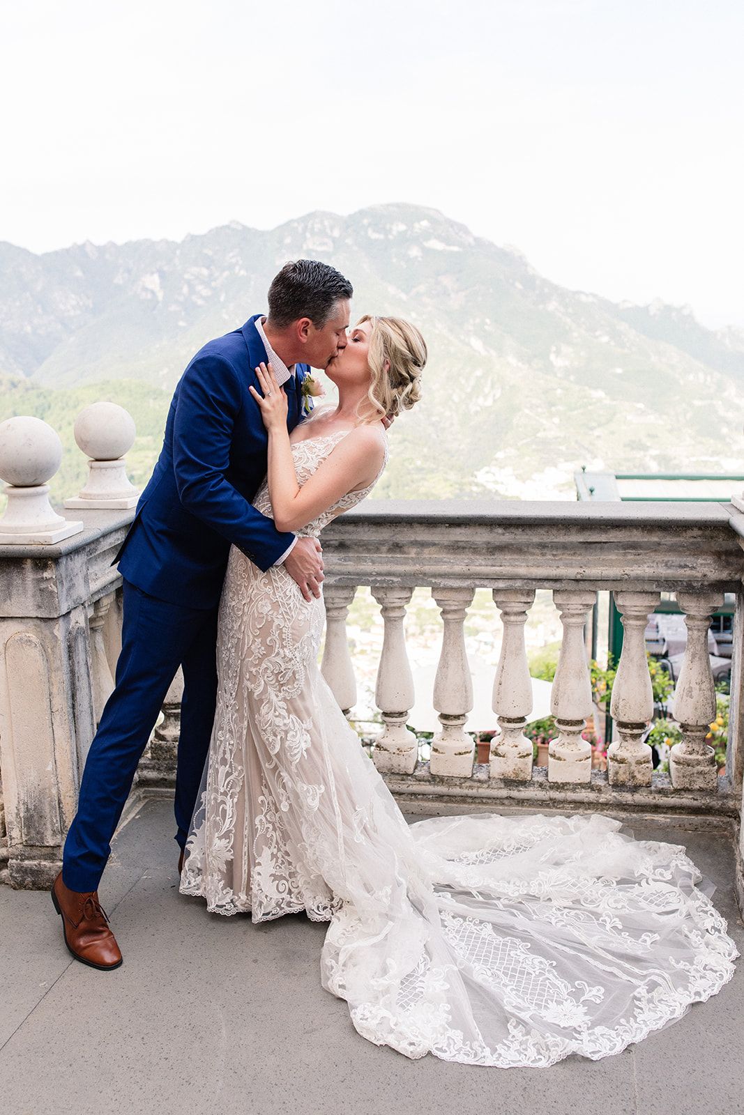 Groom kisses his bride on the lips after the ceremony of their destination wedding in Italy, with mountains in the background