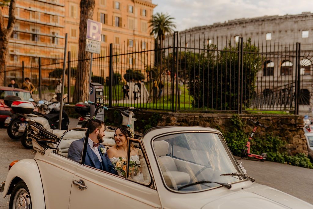Bride and groom riding a white vintage car on the streets of Rome when they eloped in Italy