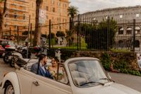 Bride and groom riding a white vintage car on the streets of Rome when they eloped in Italy