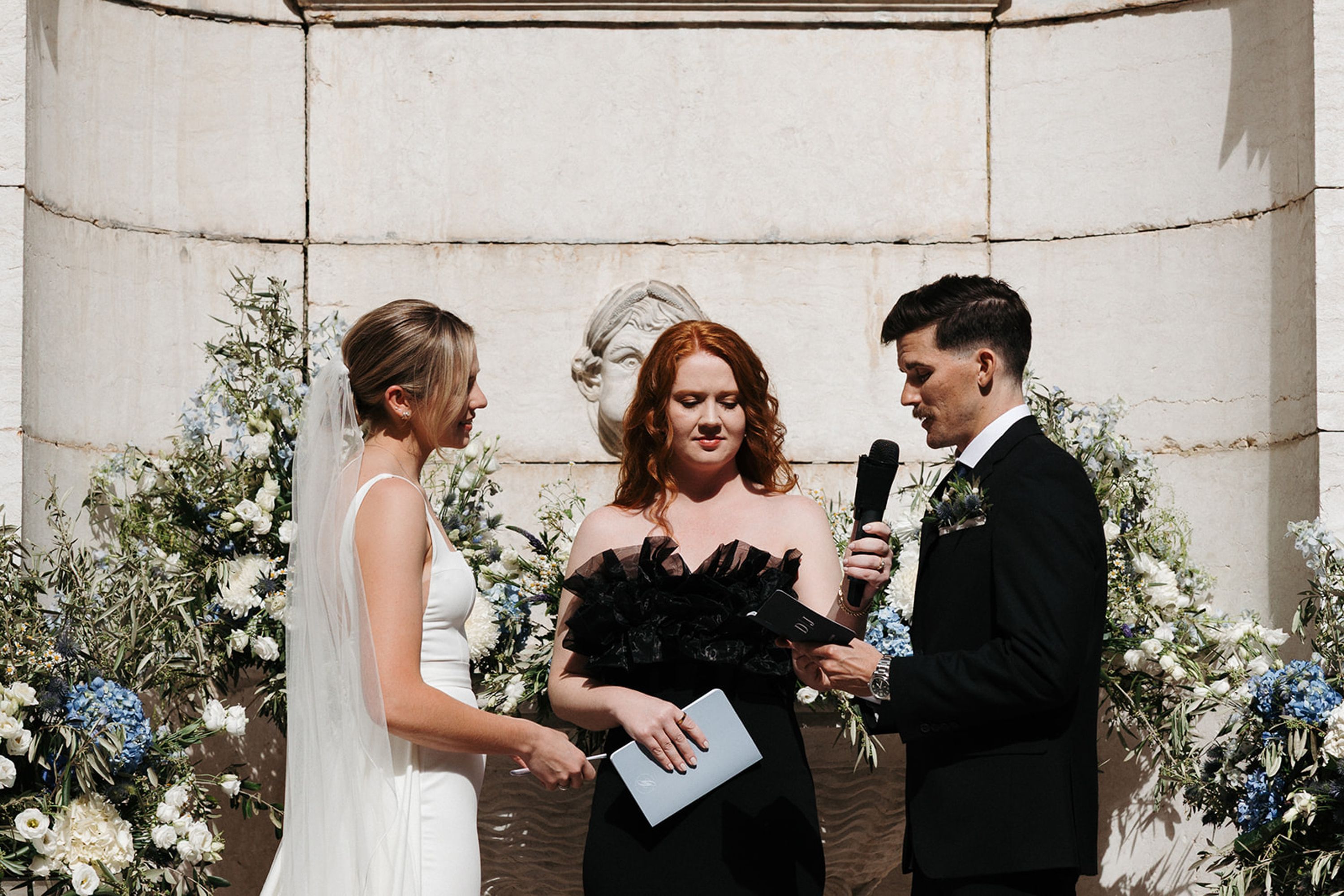 Groom reading vows beside the bride during a small wedding in Portugal with romantic floral arrangements