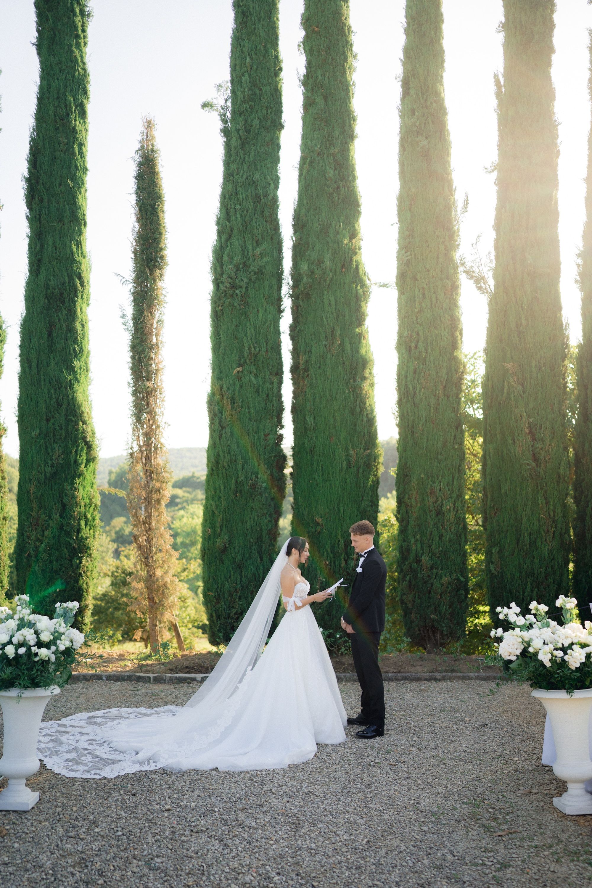 Bride reciting vows to her groom in an intimate wedding in Italy with cypress trees and Tuscan scene in the background