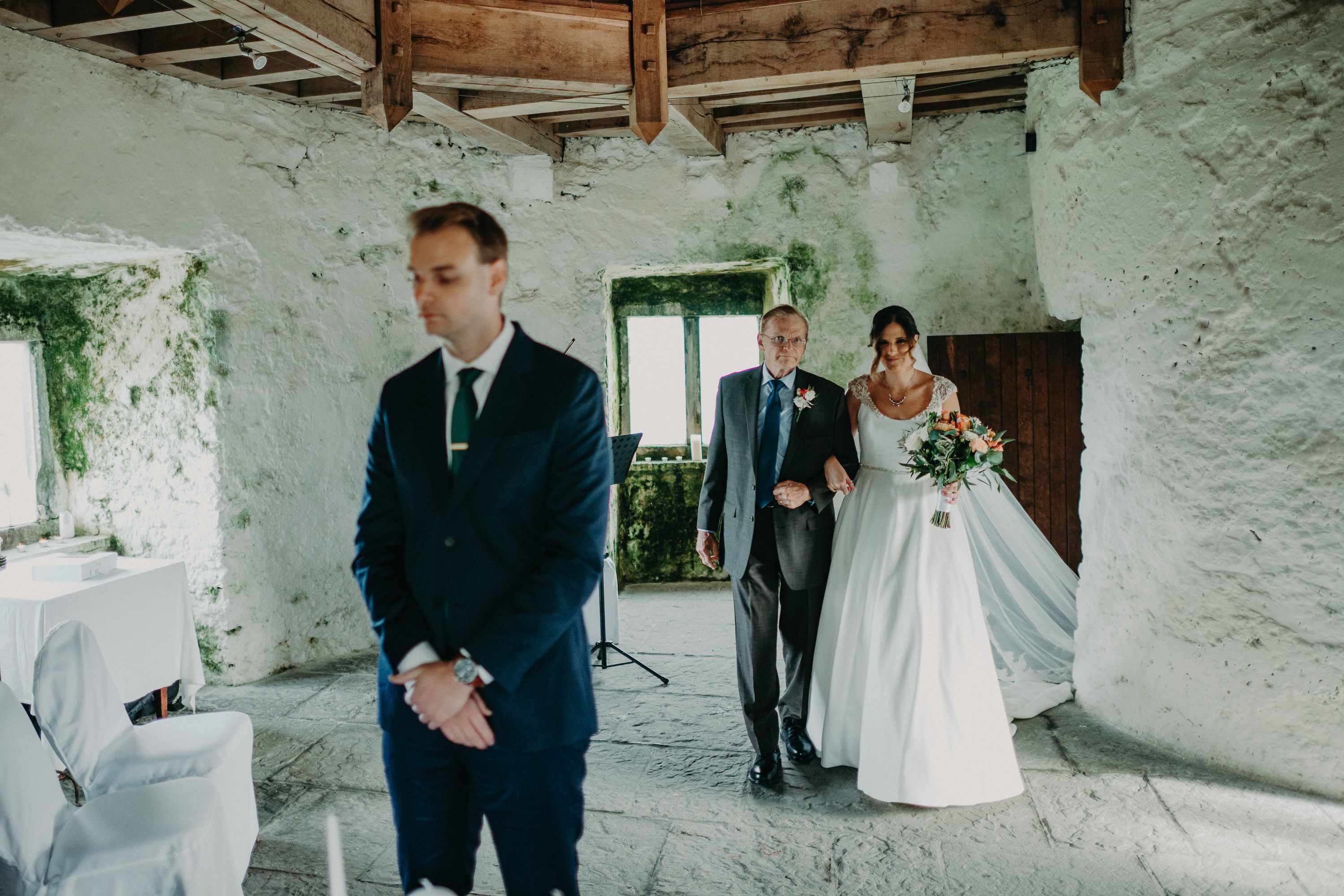 Bride enters the ceremony with her father during a small wedding in Ireland inside a romantic castle setting.