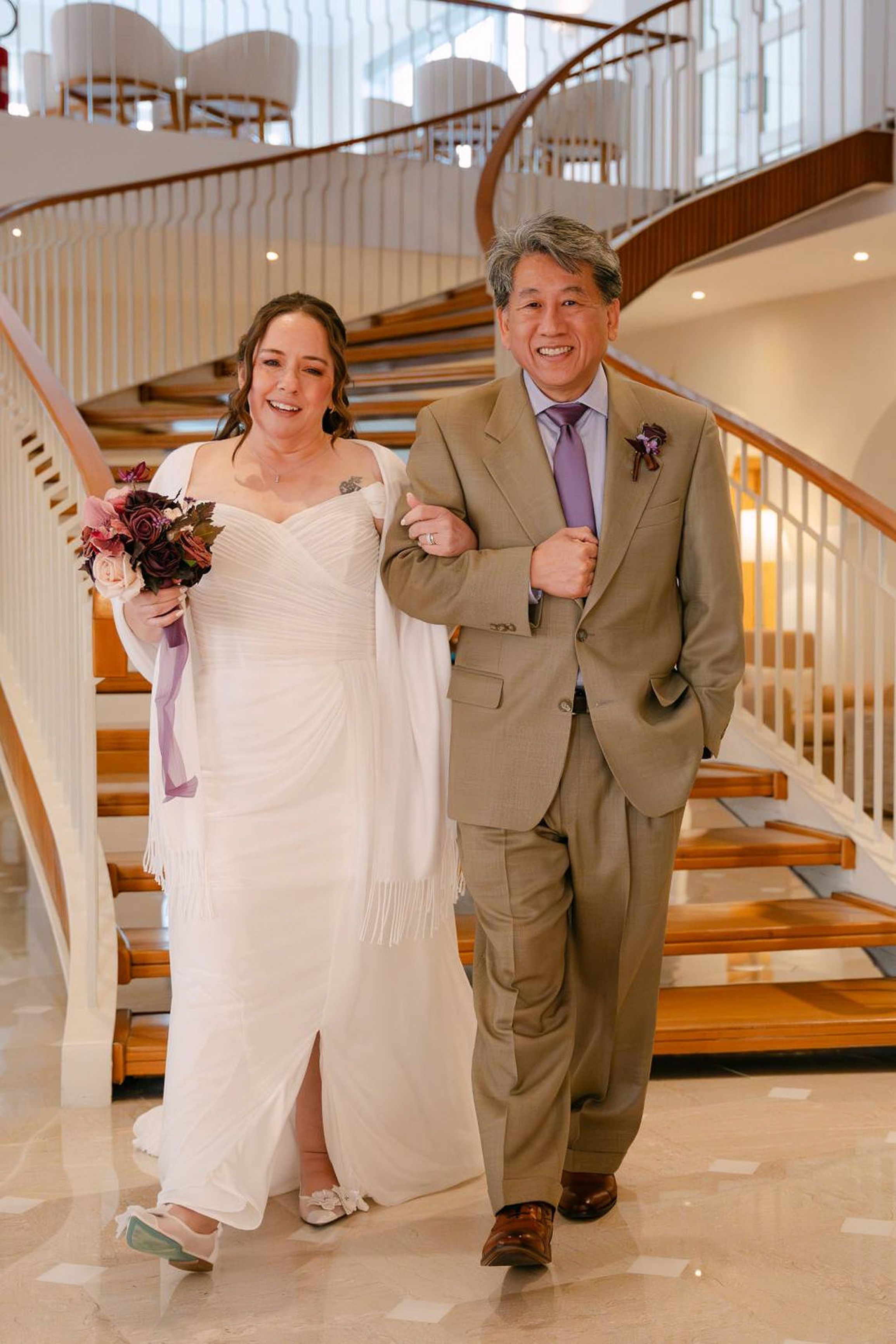 Newlyweds walk arm in arm through a grand staircase venue after a small wedding in Italy