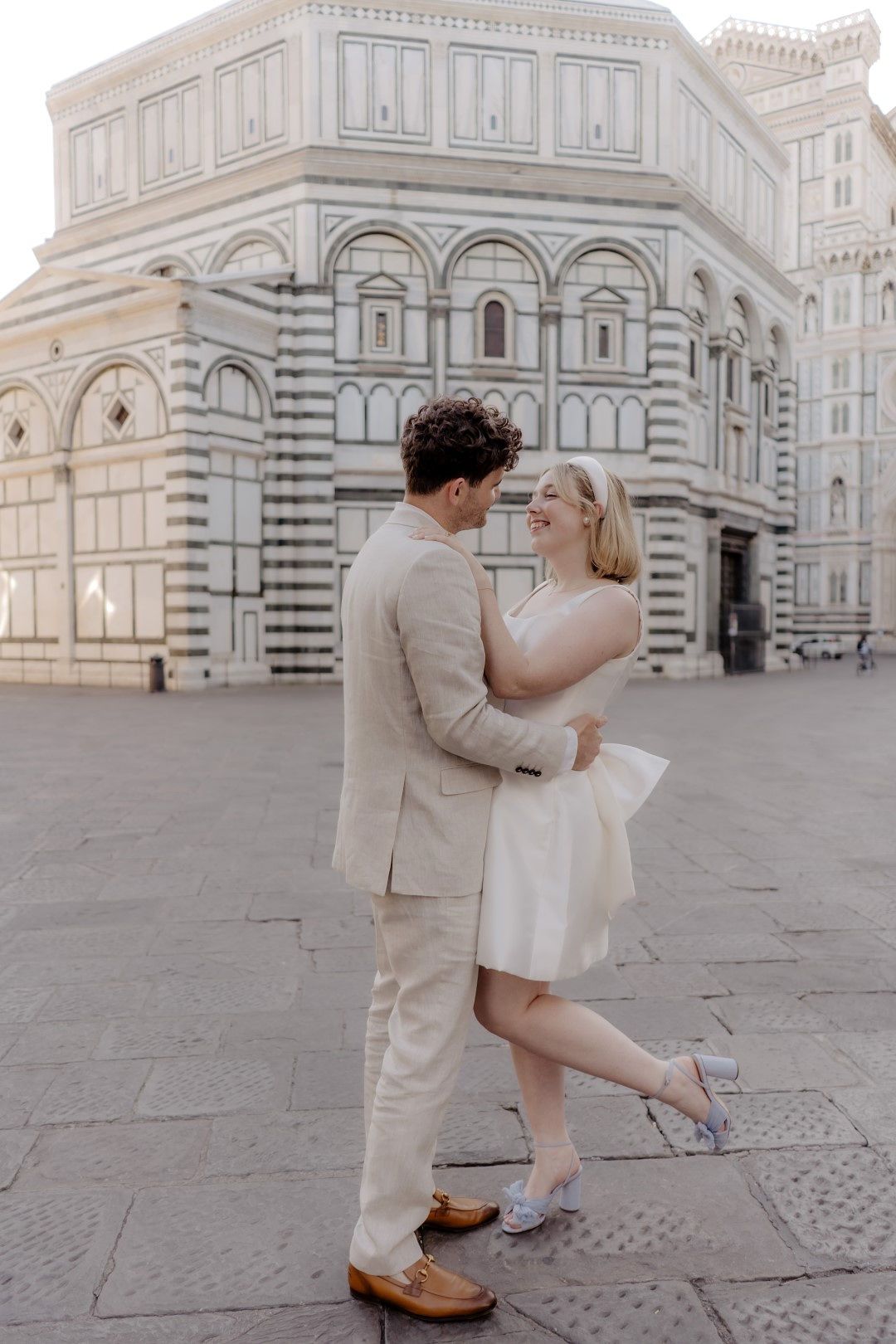 A couple in casual attire having an elopement photoshoot in Italy with the Florence Baptistery in the background.