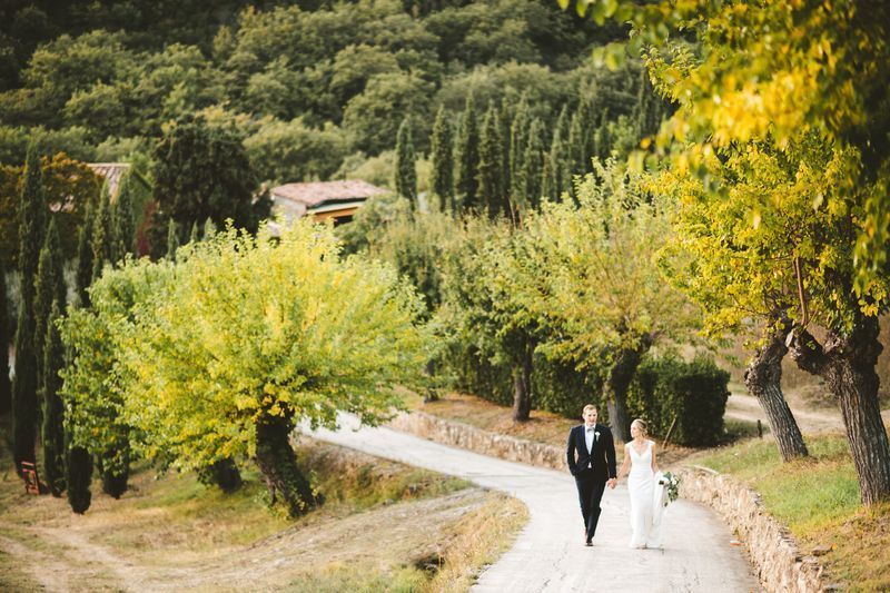 Bride and groom walking down a road in Tuscany
