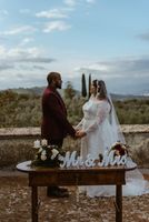 Bride and groom holding hands during their destination wedding ceremony in Italy with Tuscan views in the background