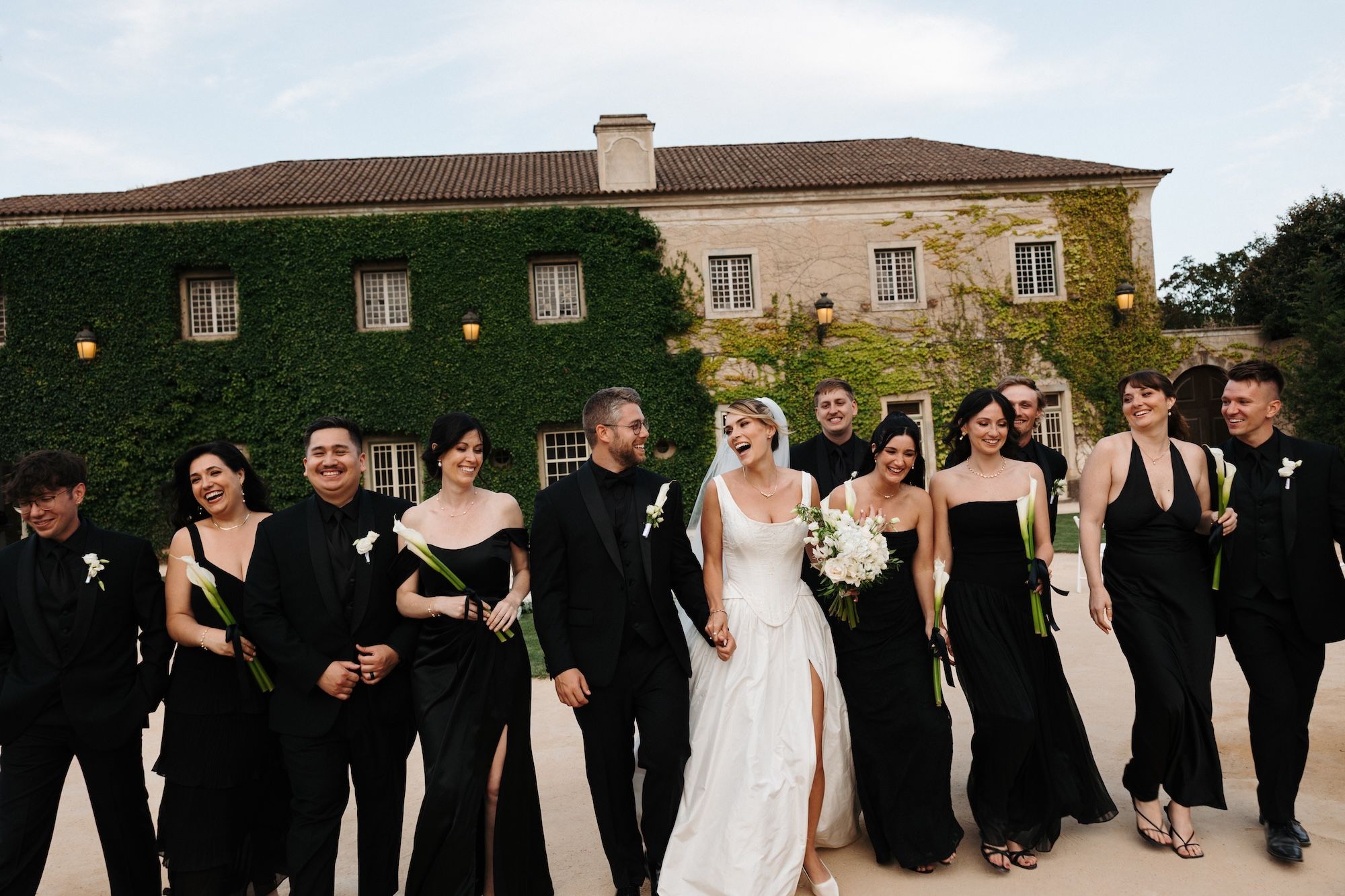 Newlyweds with their entourage in black walking in the courtyard of the palace where they got married in Portugal