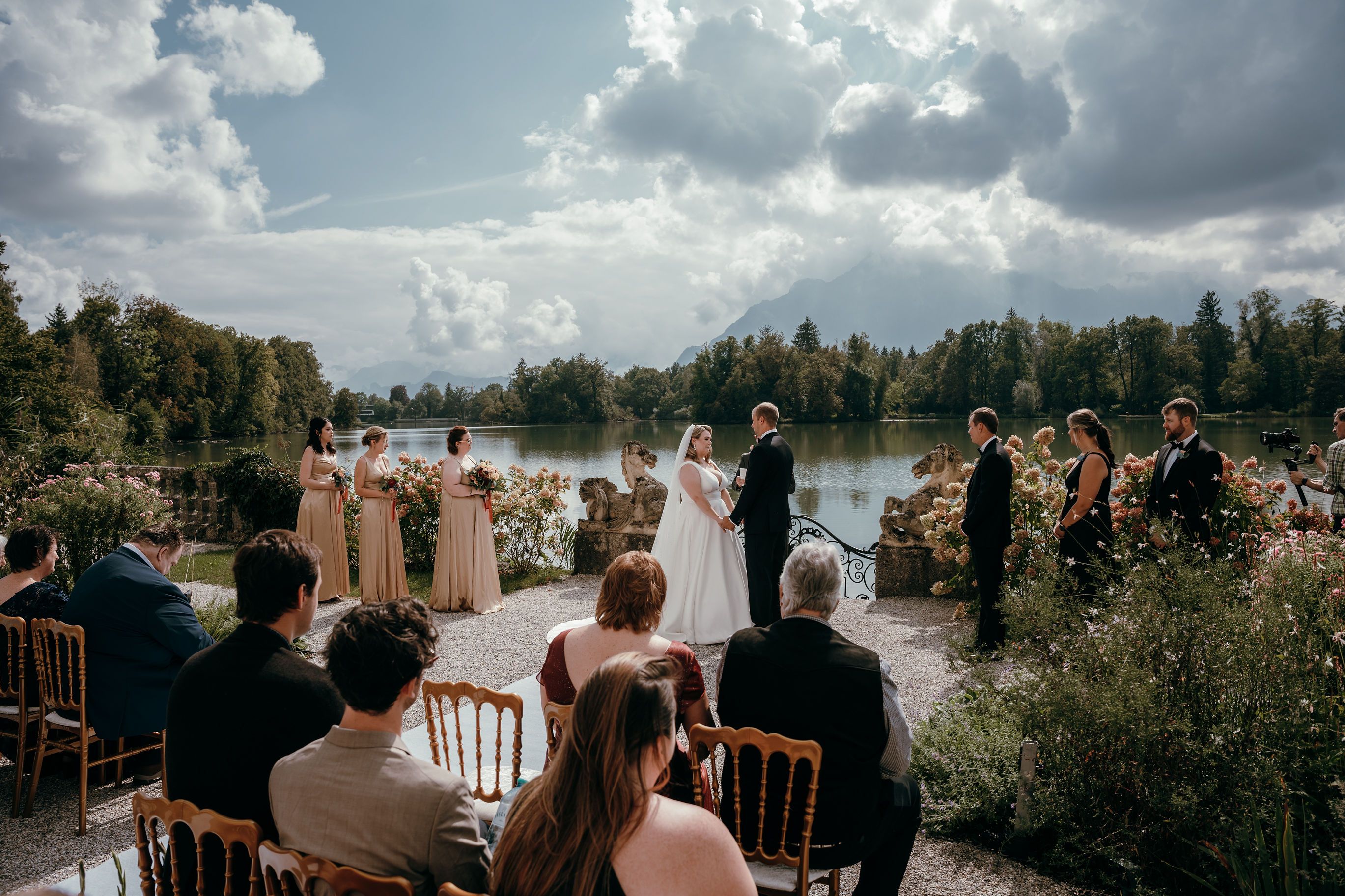 Guests watching a lakeside wedding ceremony near Salzburg, mountains on the horizon