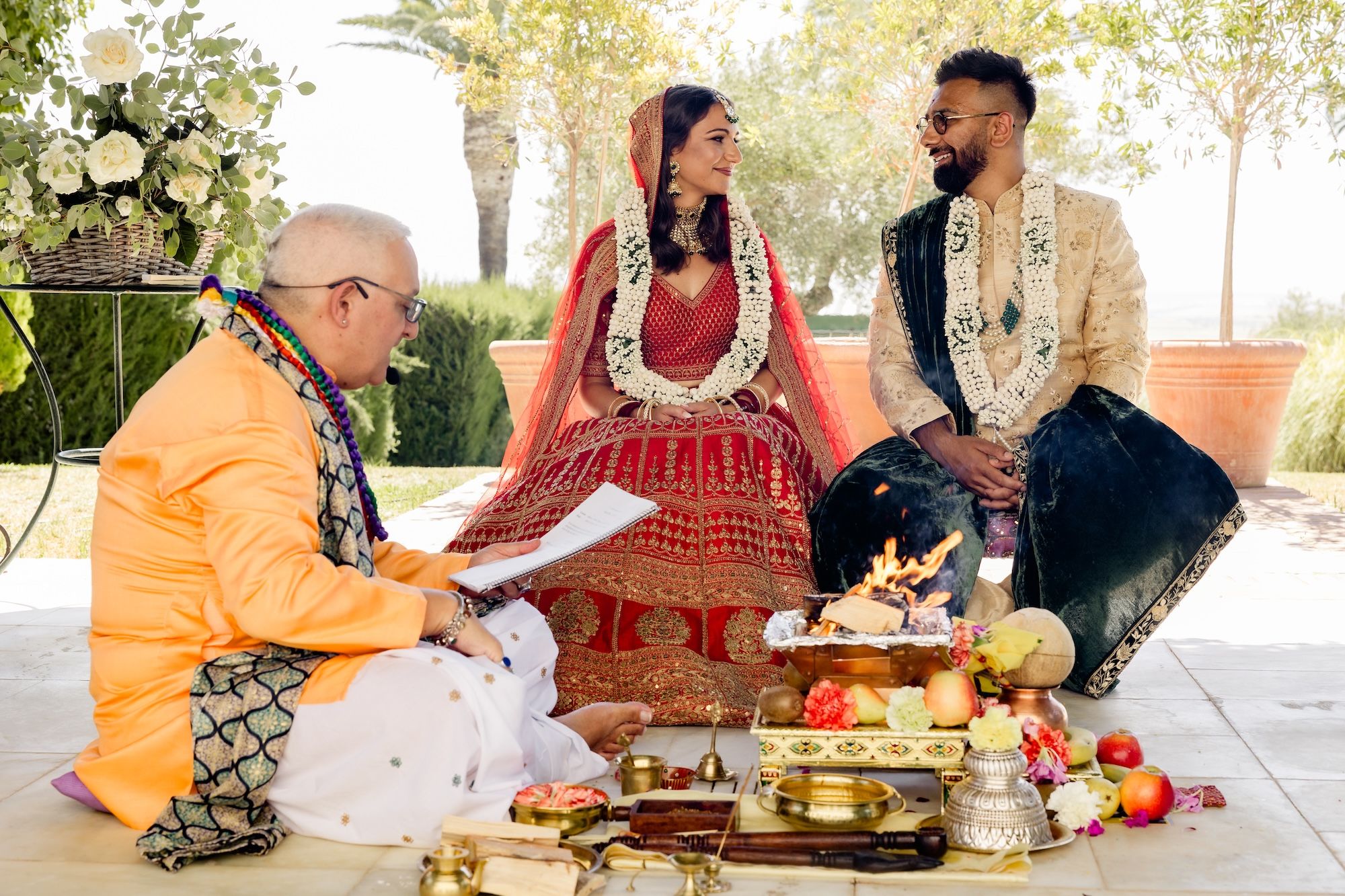 Bride and groom look at each other during the ceremony of their intimate wedding in Spain, while the officiant reads a Hindu ritual