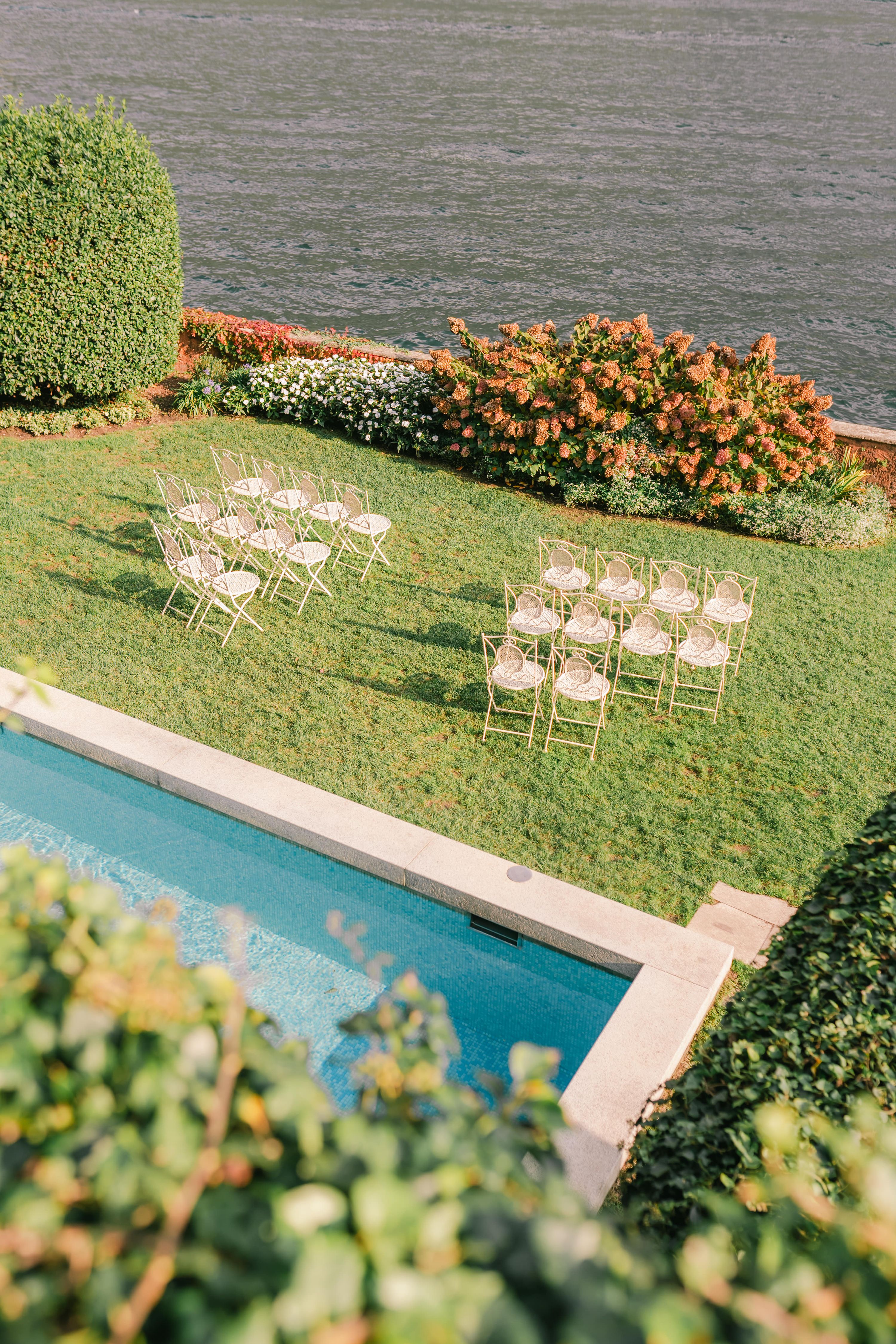 Chairs arranged for a micro wedding in Italy with beautiful elements - a pool, Lake Como, and beautiful flowers