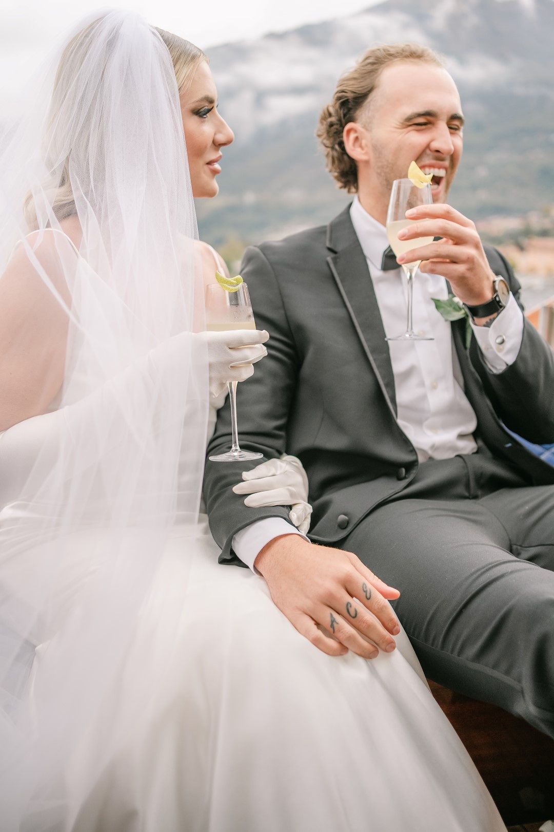 A bride and groom drinking champagne while riding a boat on their way to their small wedding in Italy