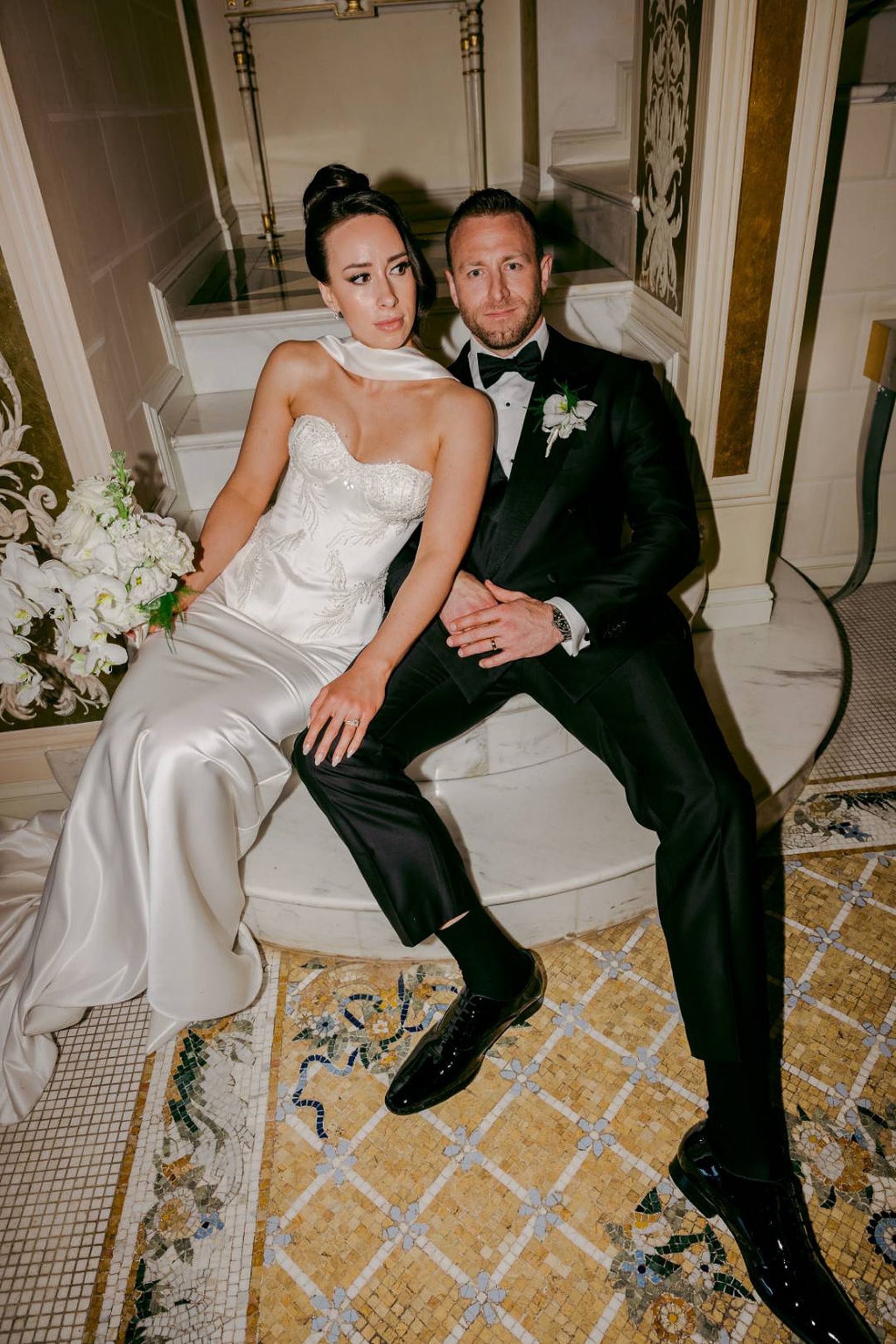 Stylish bride and groom seated on marble steps at a small wedding in Italy reception venue