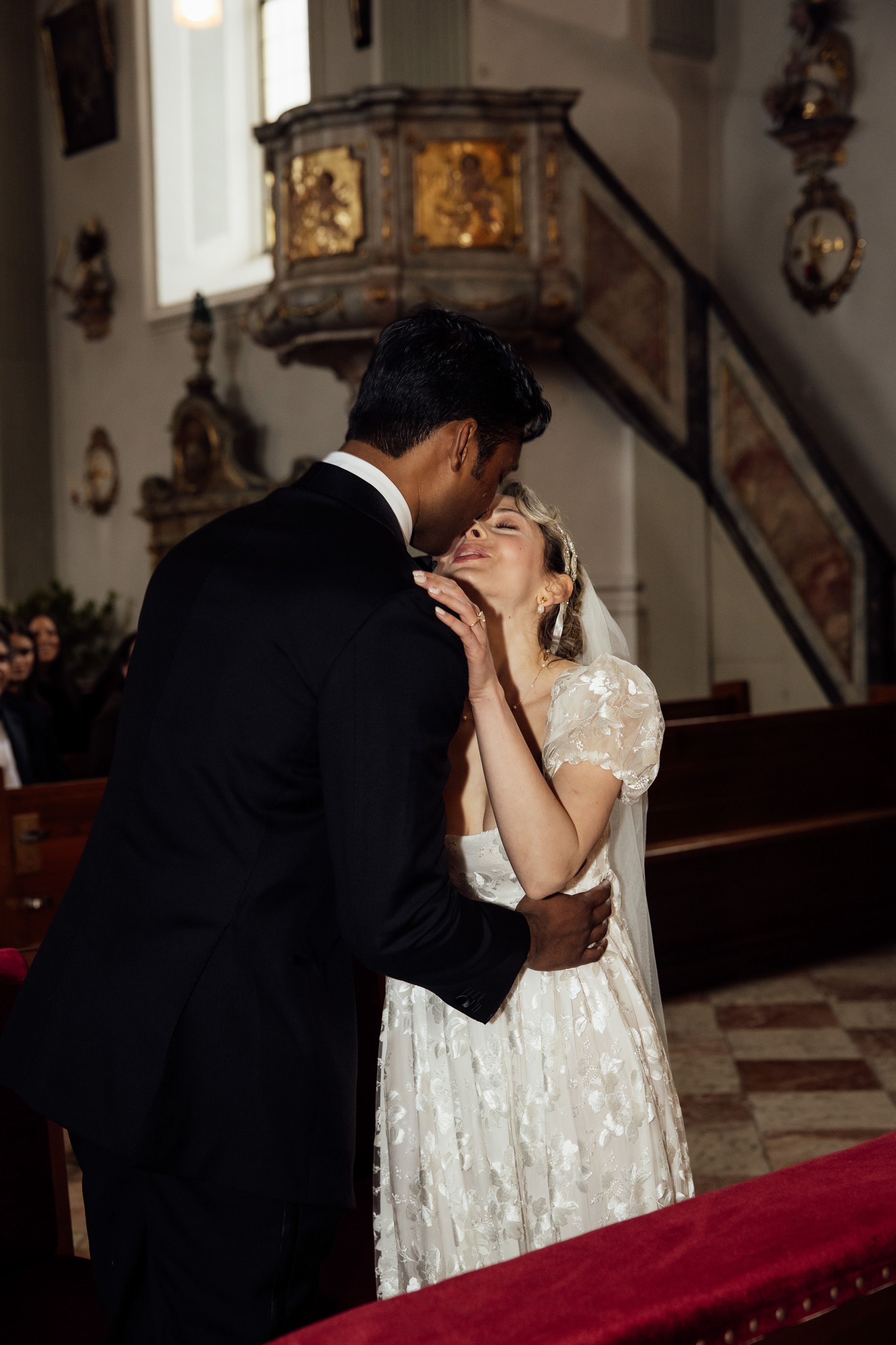 Newly married couple share their first kiss inside a historic church during an intimate wedding in Austria