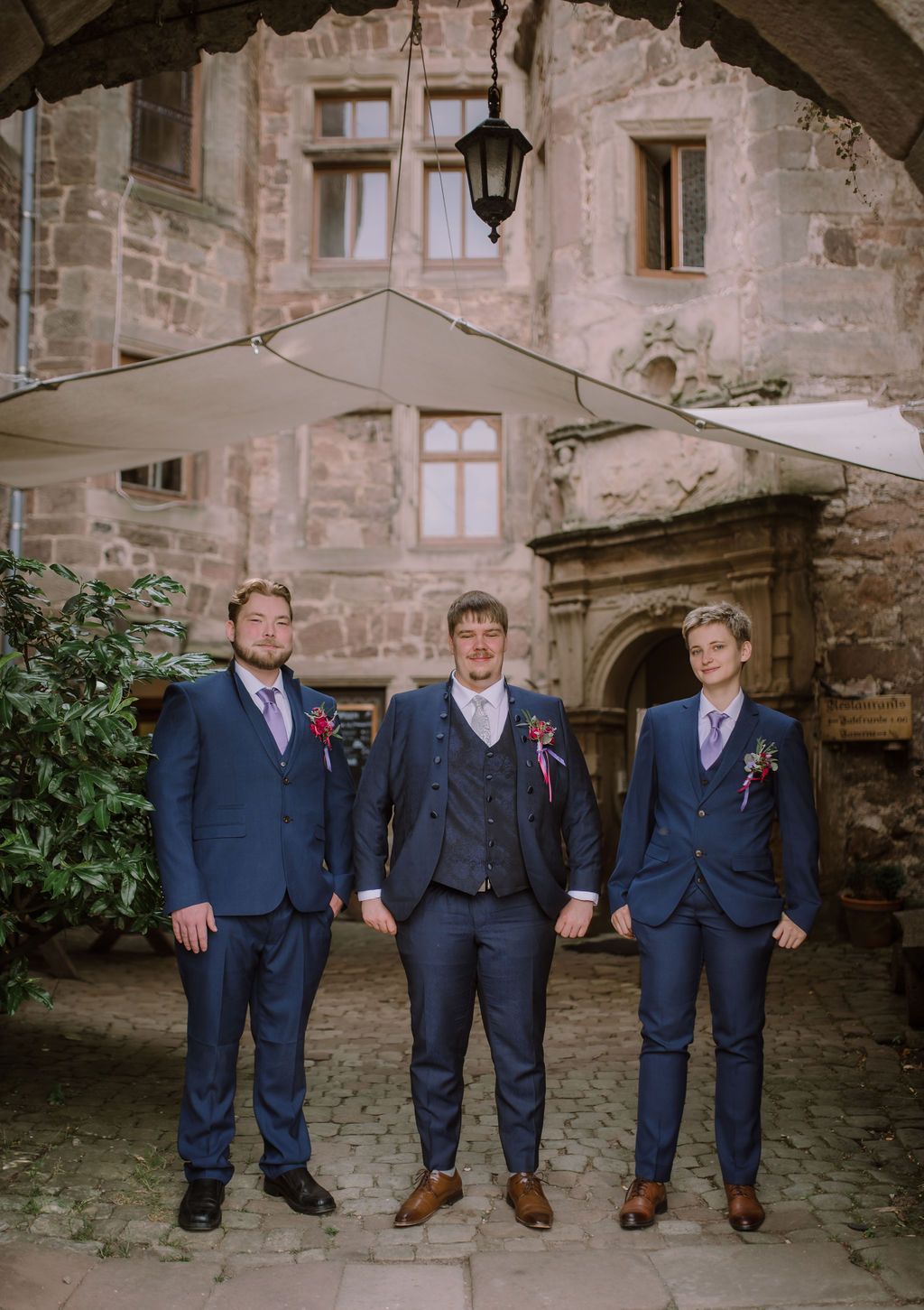 A groom and his groomsmen having their portrait taken before the castle walls before a small wedding in Germany