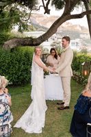 Bride and groom holding hands in front of their guests and their celebrant with the Amalfi Ciast in the background