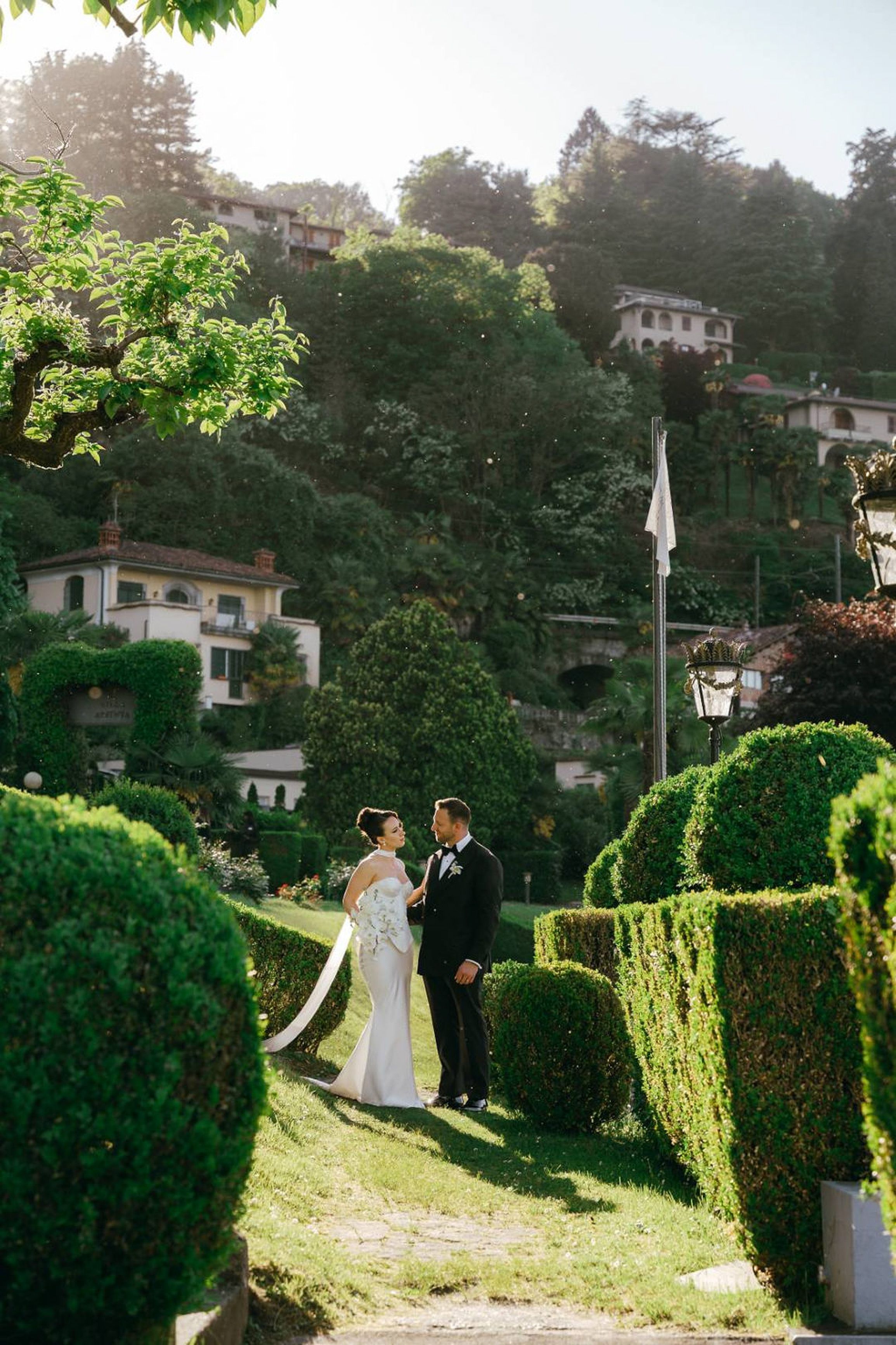 Couple standing among lush garden hedges during a romantic small wedding in Italy