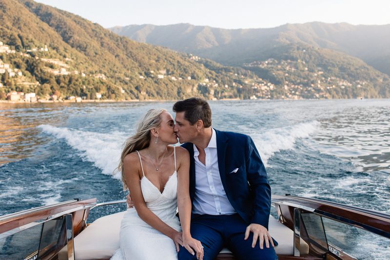 Bride and groom kissing on a boat on Lake Como
