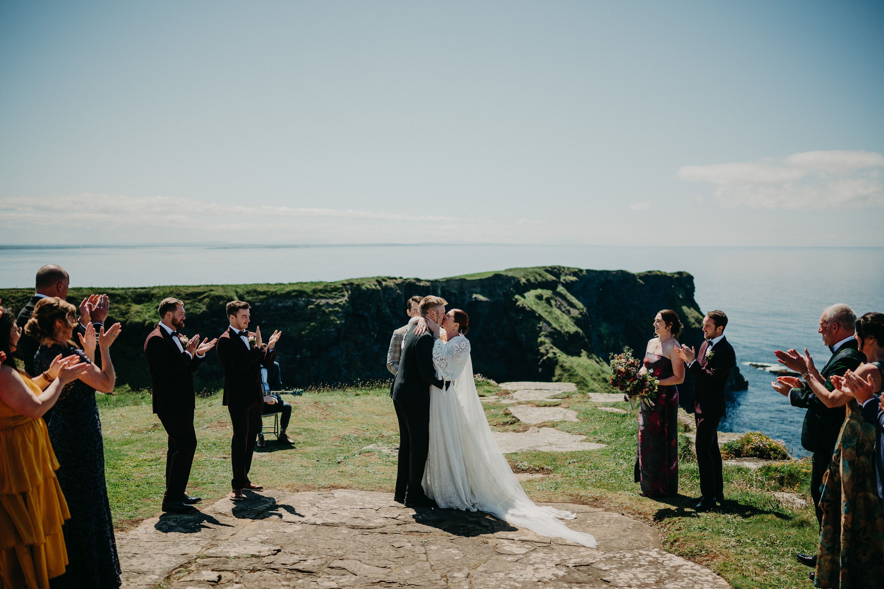 A bride and groom kissing on top of a cliff during their small wedding in Ireland