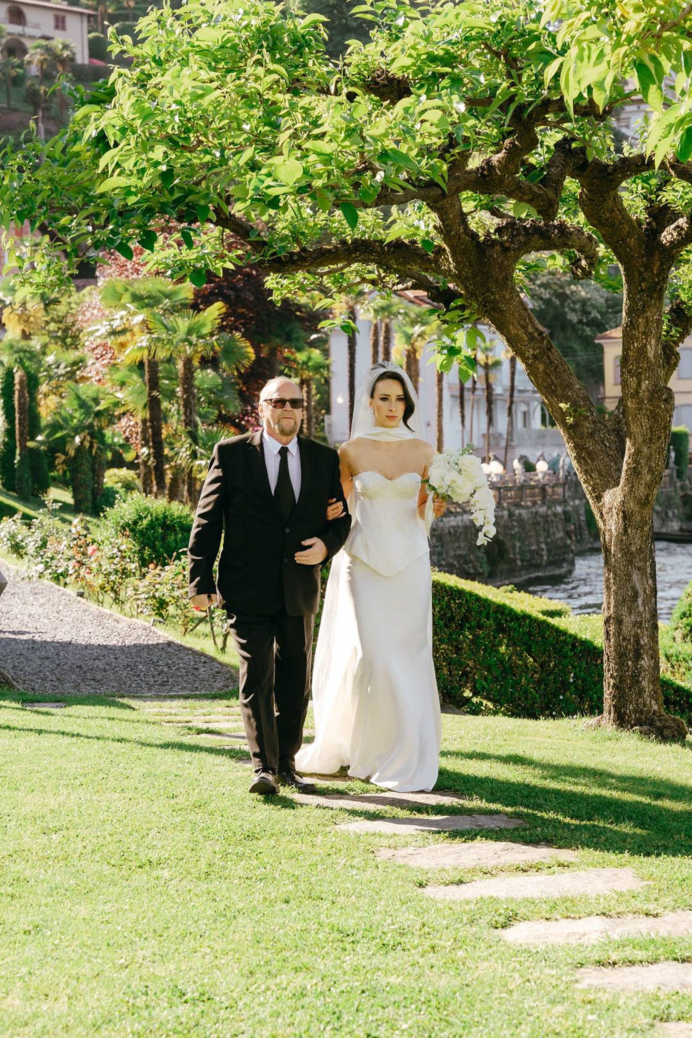 Bride walking with her father through villa gardens for an intimate wedding in Italy