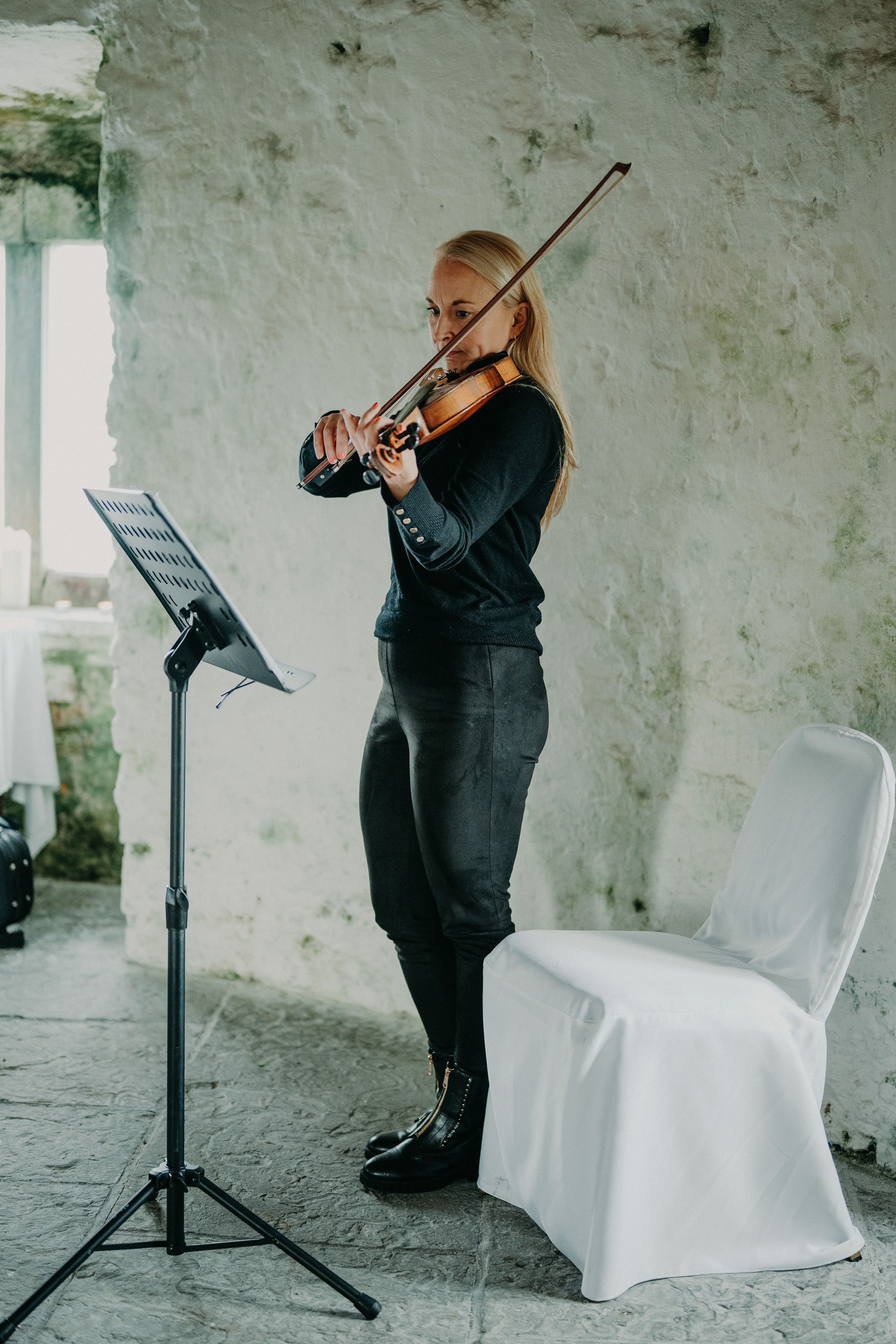 Violinist performing live music during a small wedding in Ireland inside a historic stone castle.