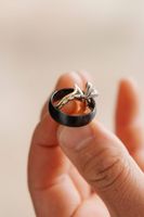 One black wedding ring for the groom and one two-tone ring of gold and white gold with a gem for the bride