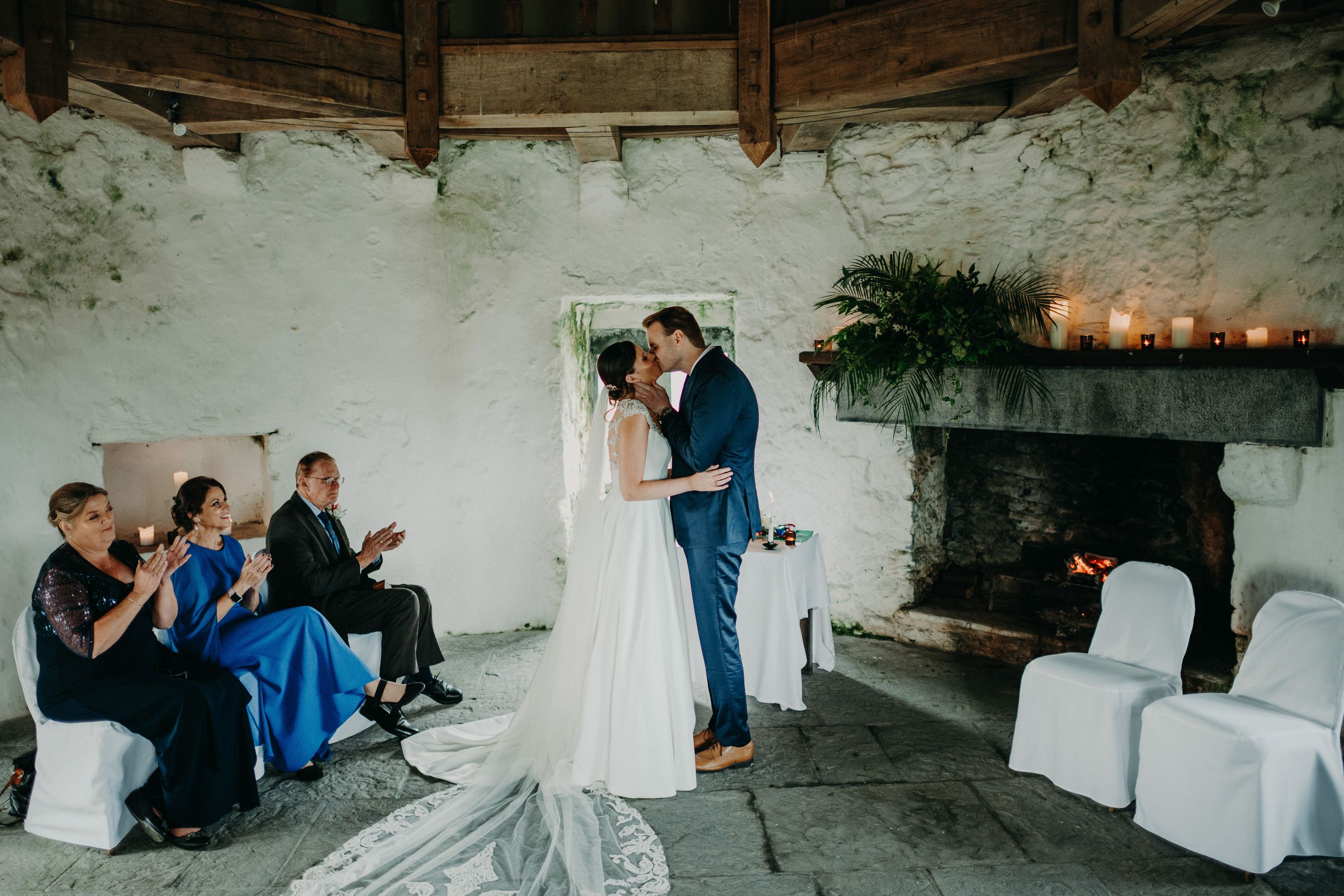Bride and groom share their first kiss beside a fireplace during an intimate wedding in Ireland.