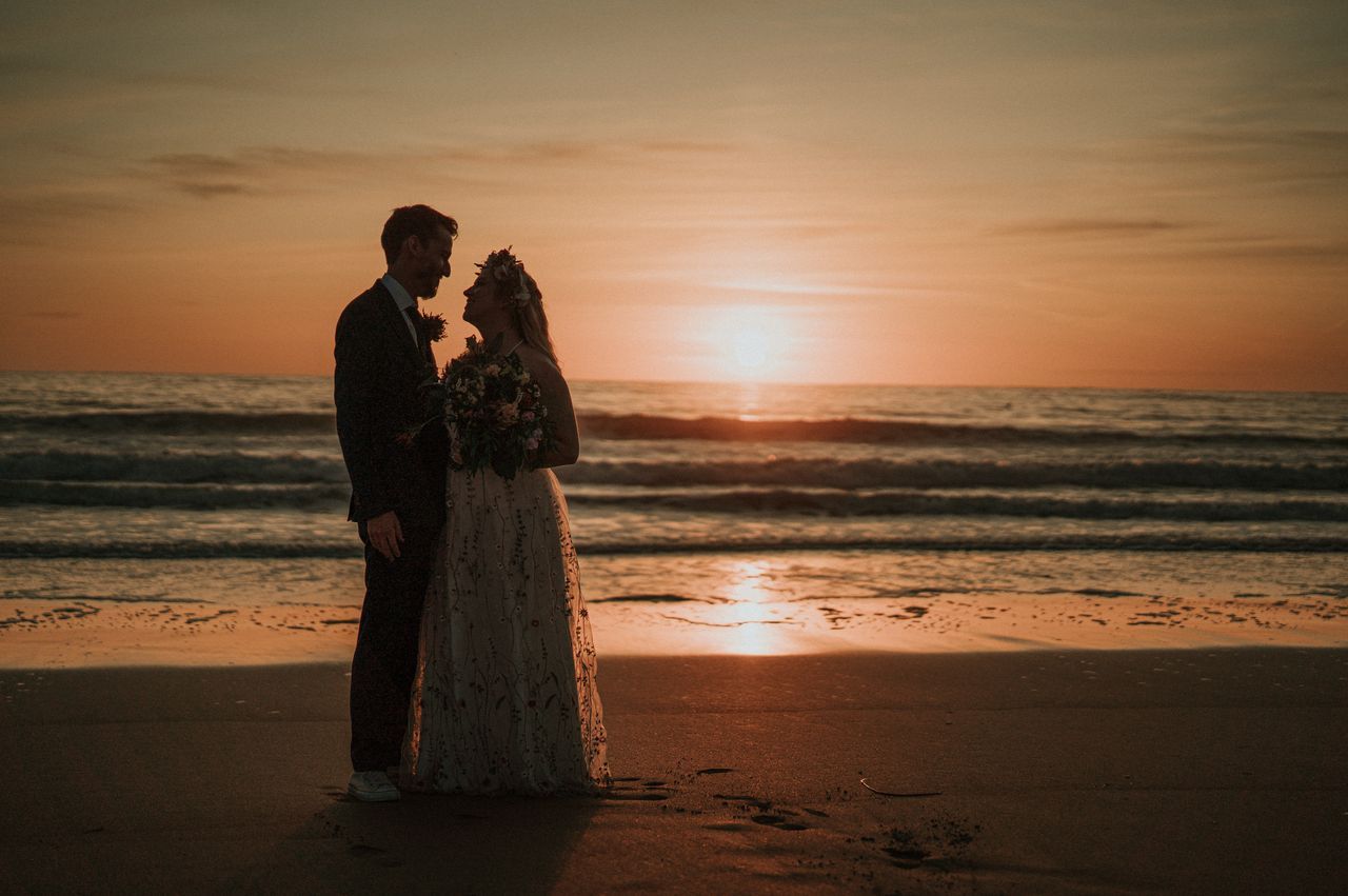Bride and groom standing on the shores of the Atlantic Ocean on a sunset during their destination elopement in Ireland
