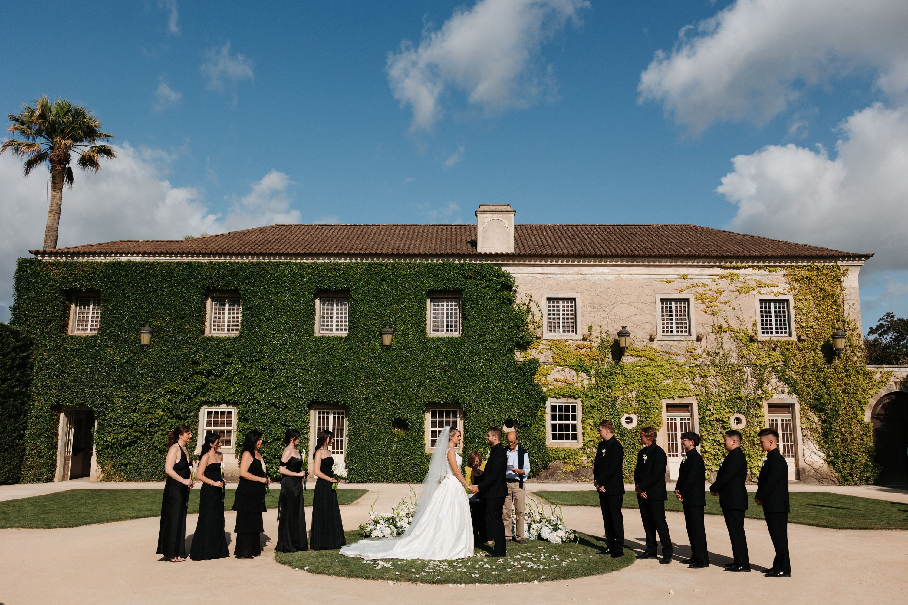 An outdoor ceremony with bride and groom, their bridesmaids, and groomsmen in front for a destination wedding in Portugal