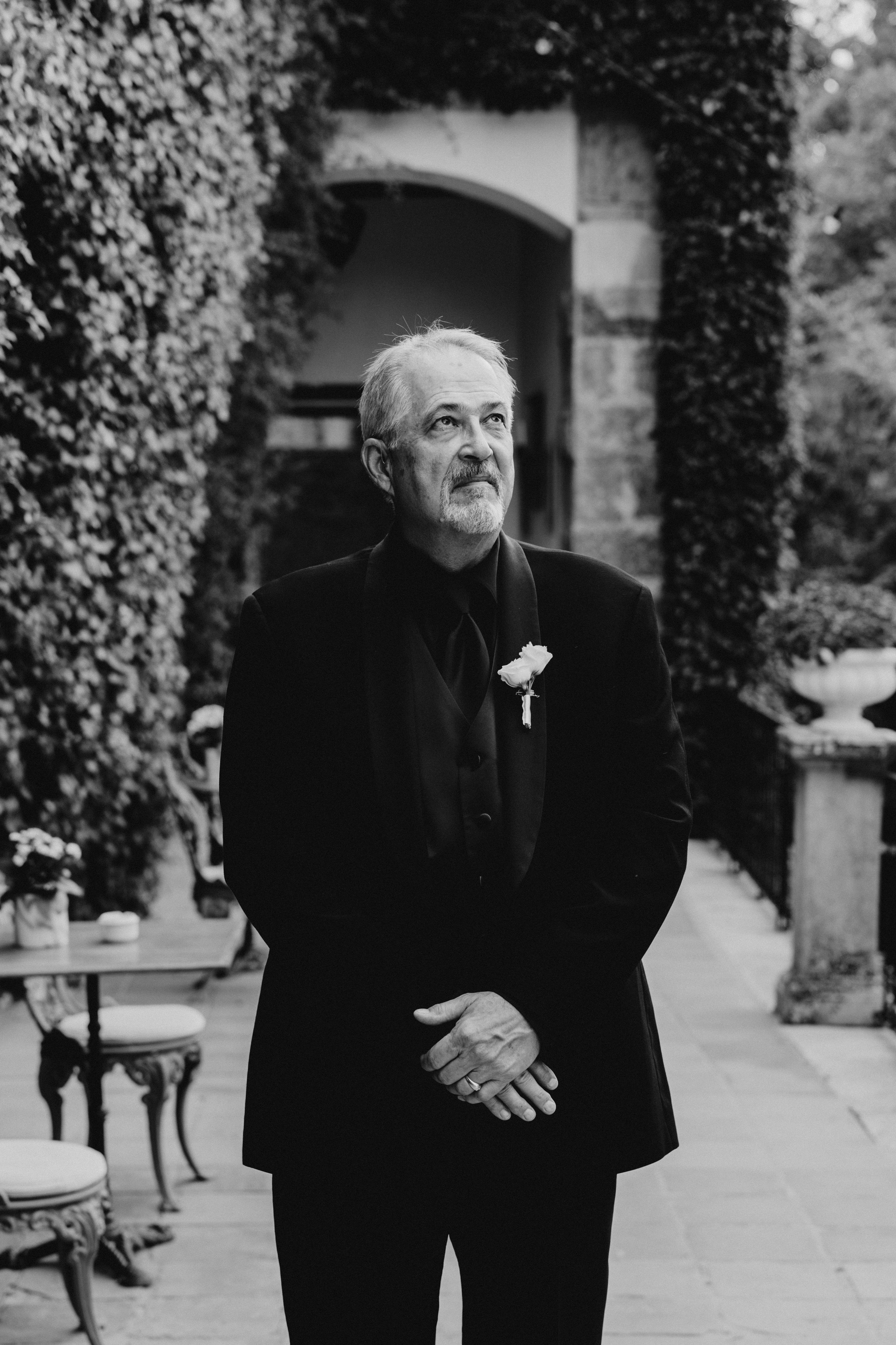Black and white photograph of the father of the bride waiting to see his daughter in her wedding dress
