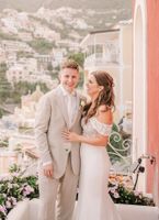 Bride looks at her groom atop a terrace with the Amalfi Coast buildings in the background during their elopement in Italy