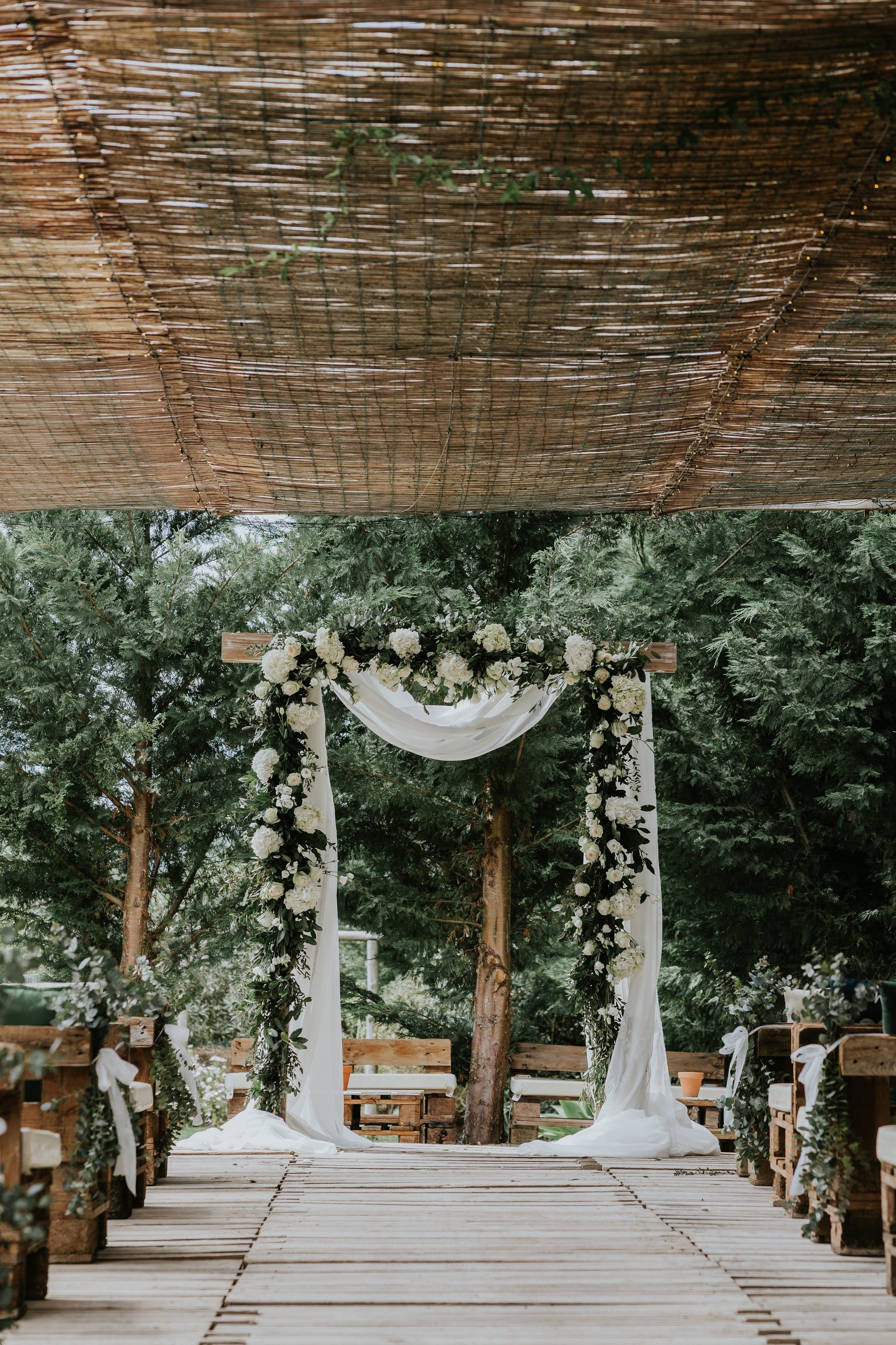 A rustic wooden wedding arch with white flowers and fresh greens